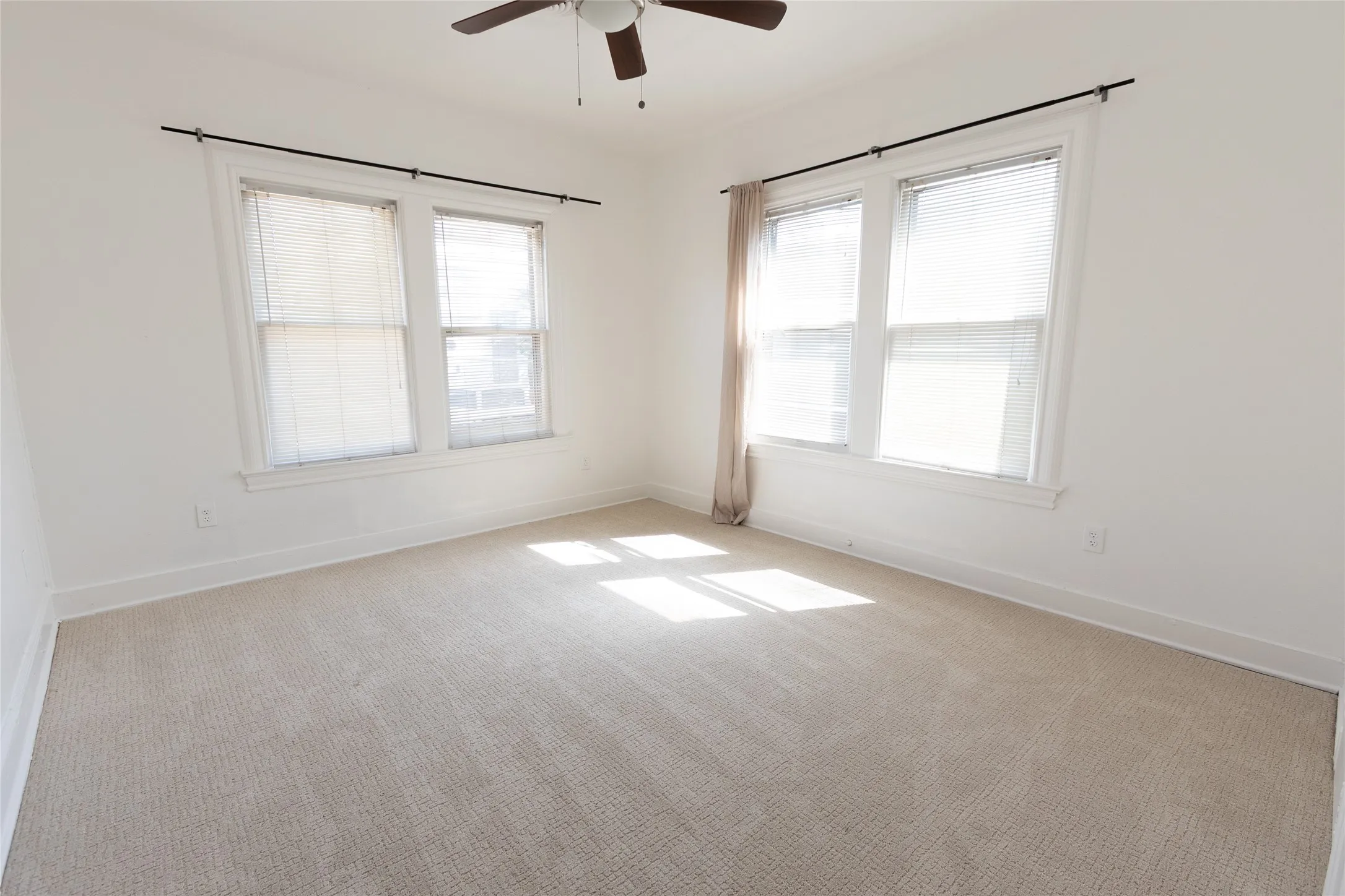 Neutral carpet flooring, white painted walls, and a ceiling fan with light fixture