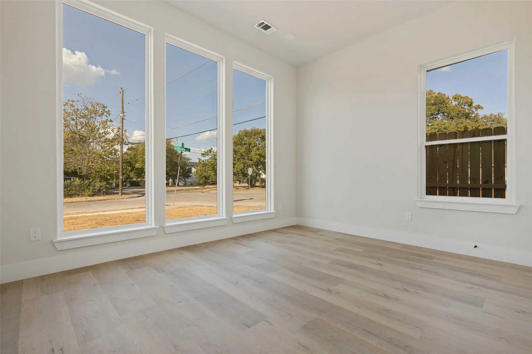 Light-toned wood-finish flooring, white walls, and multiple large windows