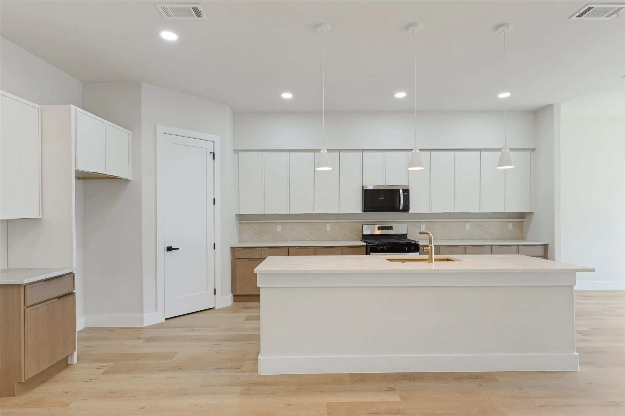 Kitchen featuring a center island, recessed lighting, pendant light fixtures, wood-finish flooring, and two-tone cabinetry