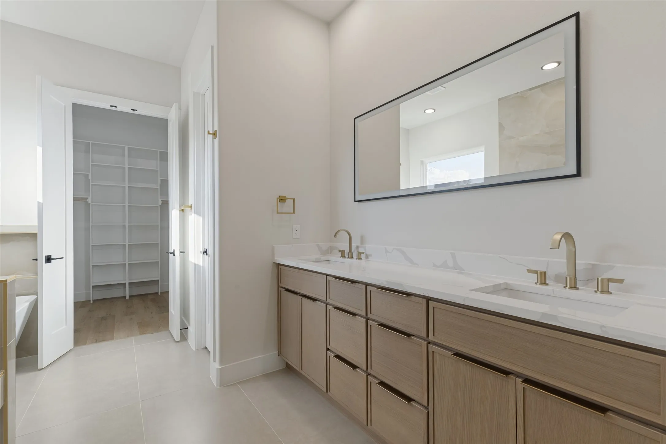 Dual vanity with integrated sinks, light wood-finish cabinetry, and stone countertops