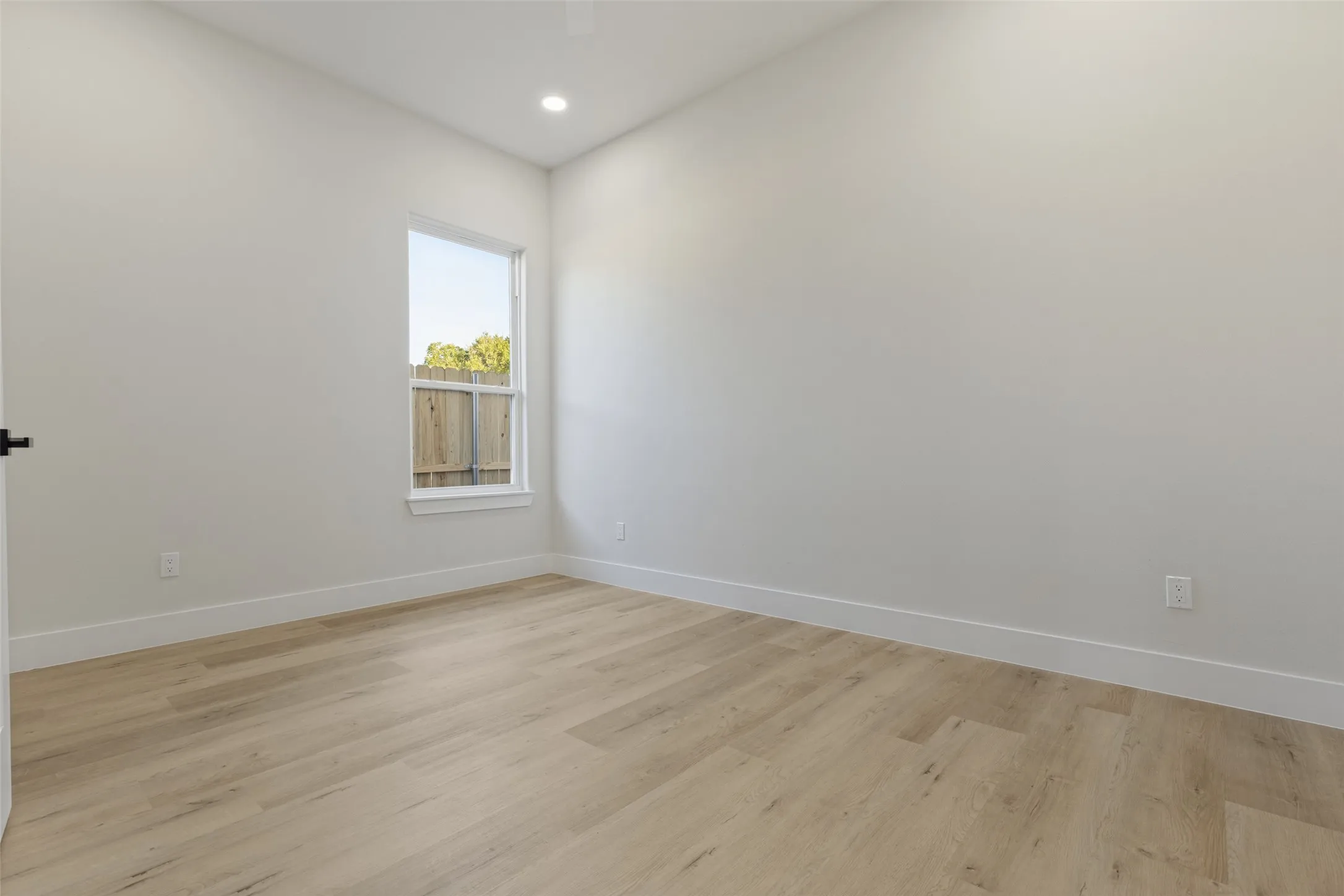 Light wood-finish flooring, white walls, and a recessed ceiling light
