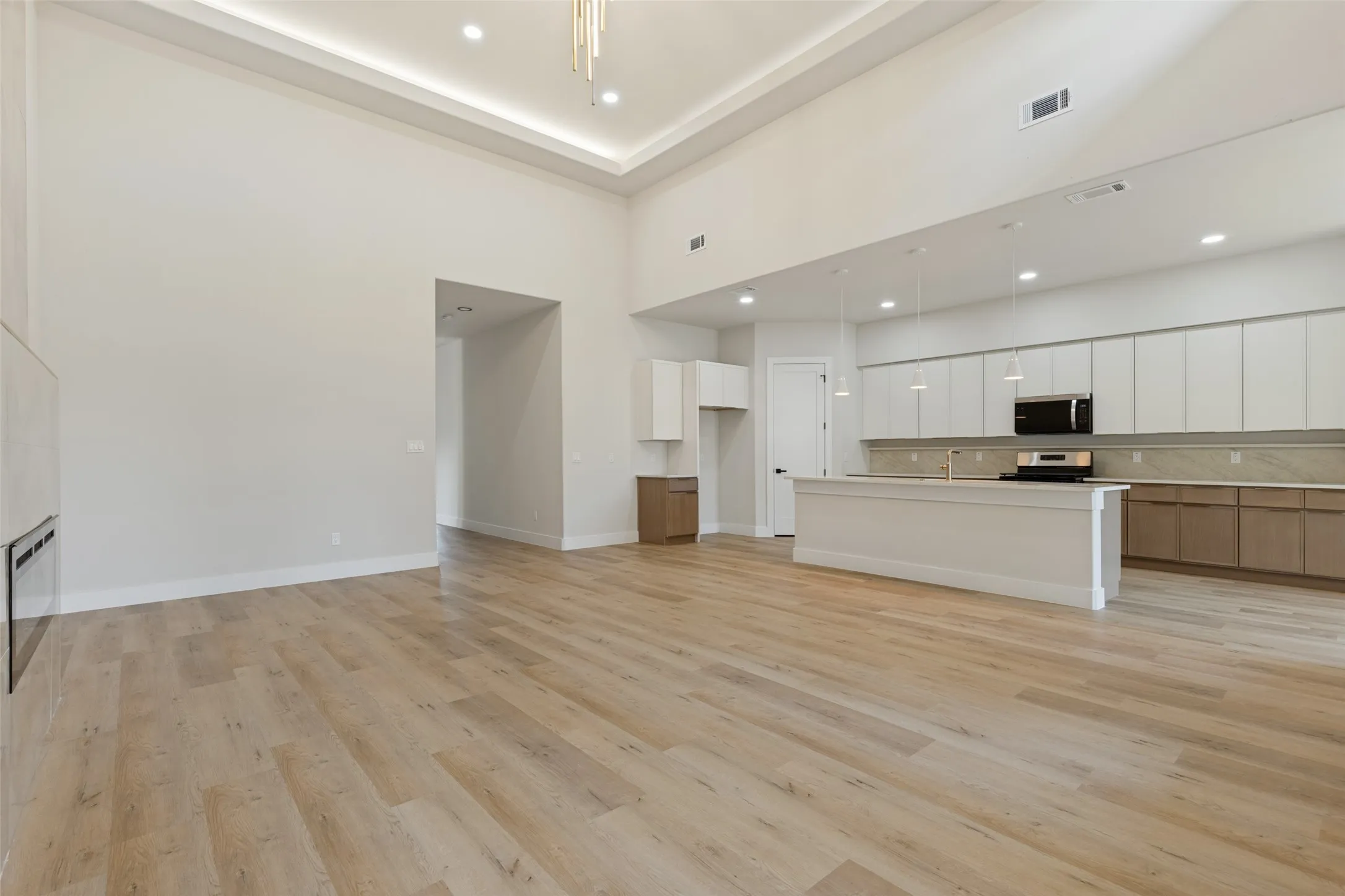 Vaulted ceiling with recessed lighting, wood-finish flooring, kitchen island with pendant lighting, stainless steel range, and built-in microwave