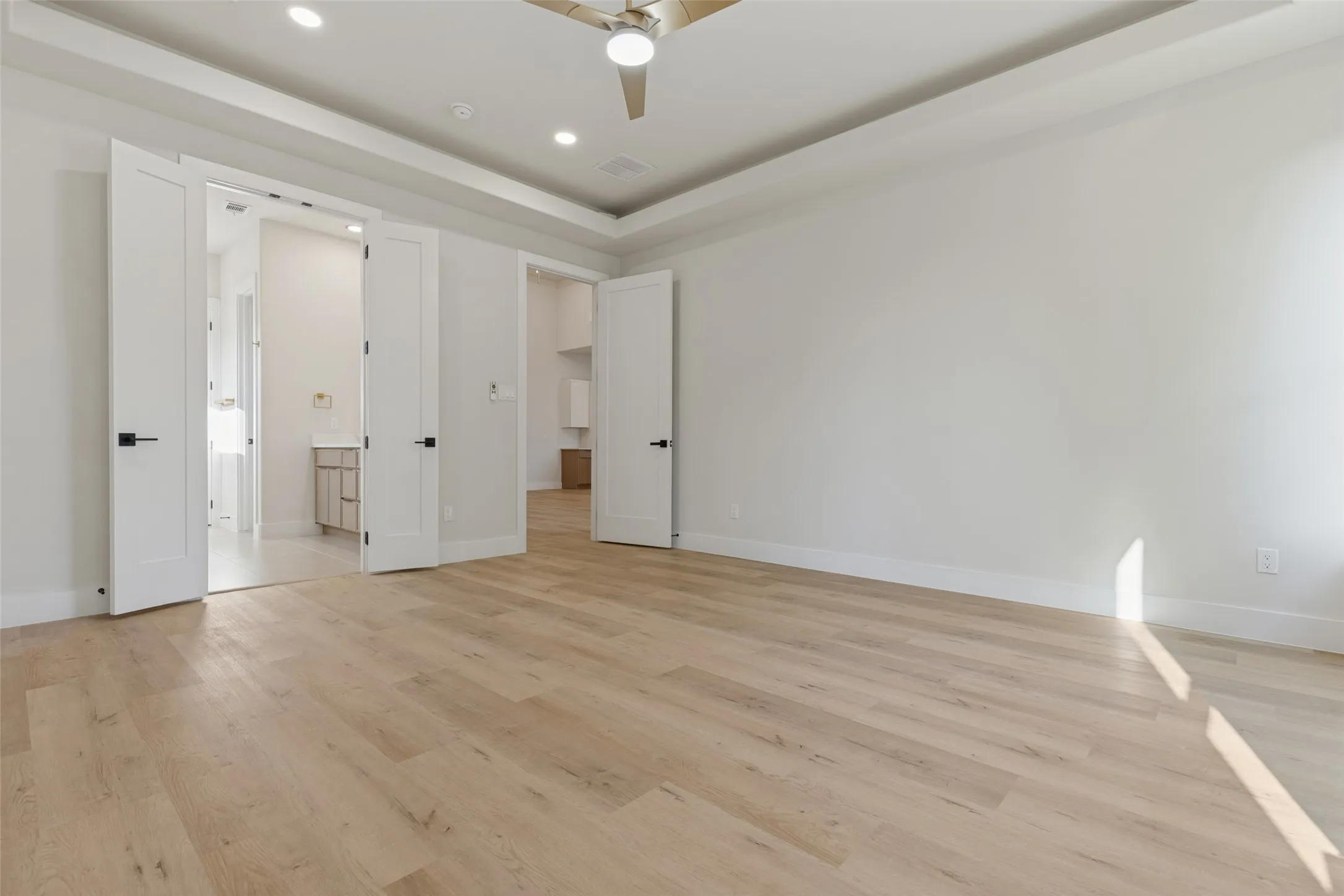 Spacious interior featuring wood-finish flooring, a tray ceiling, and recessed lighting