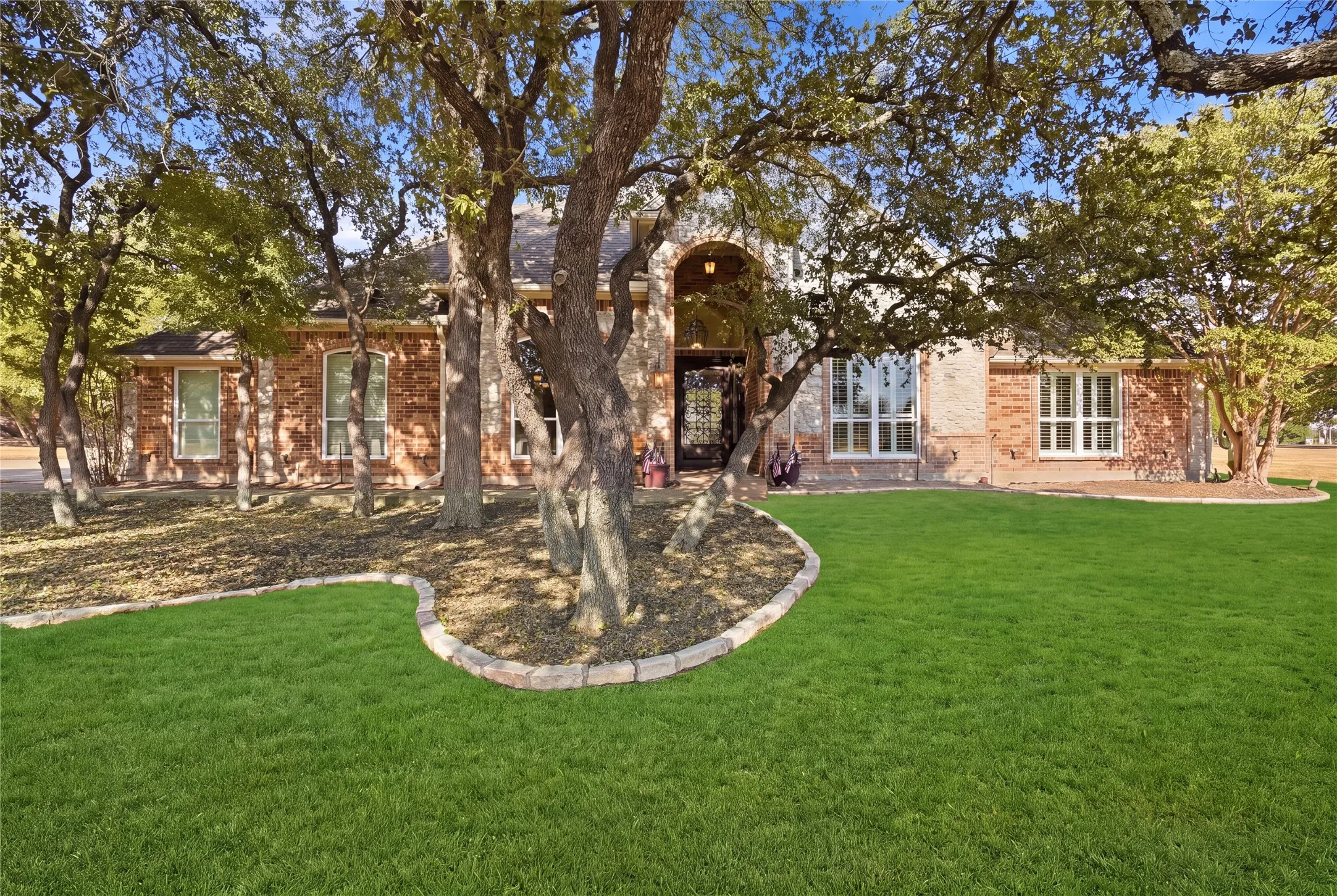 Home is located on a corner surrounded by trees.
