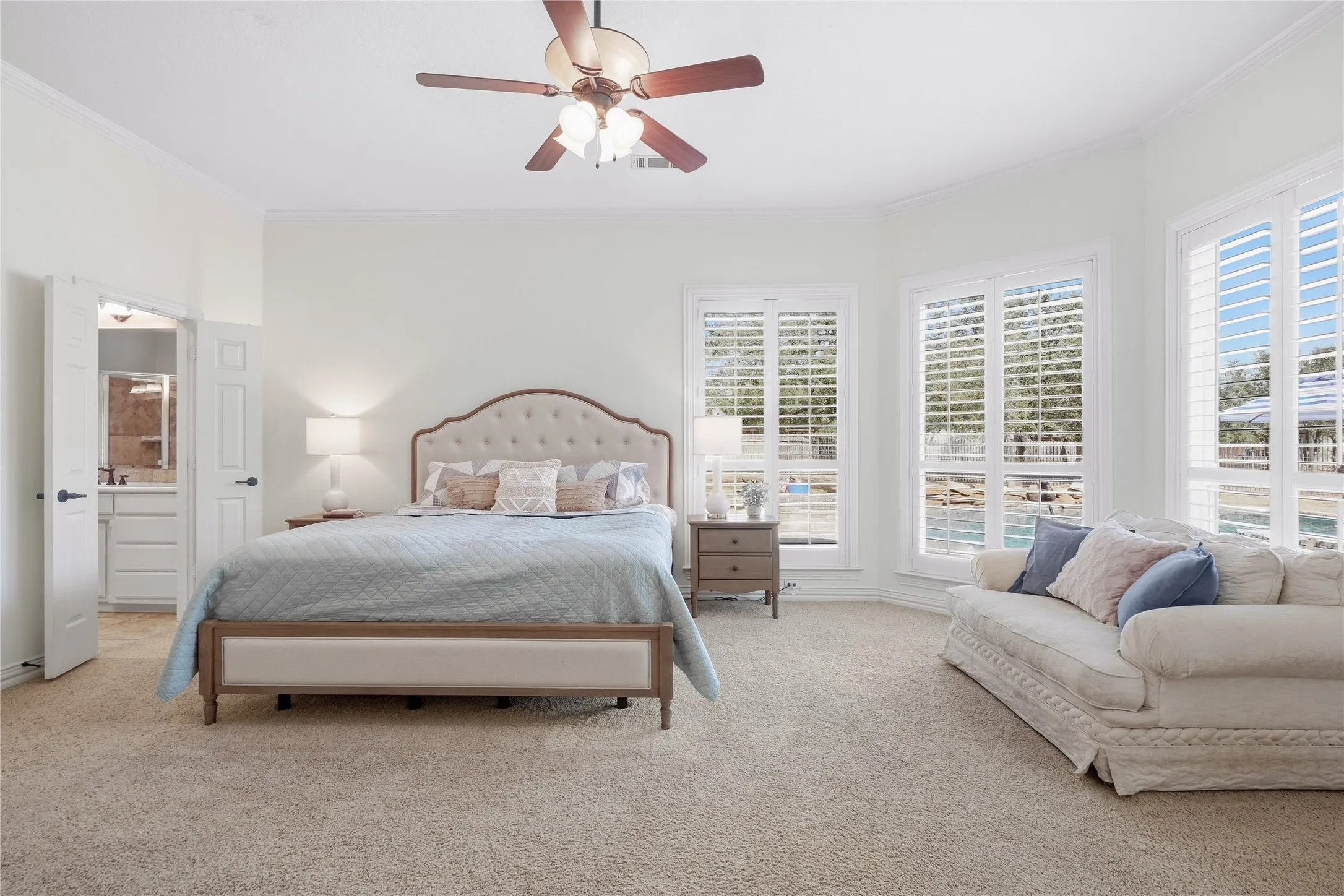 Spacious cozy primary bedroom with a sitting area and a wall of new windows overlooking the pool.