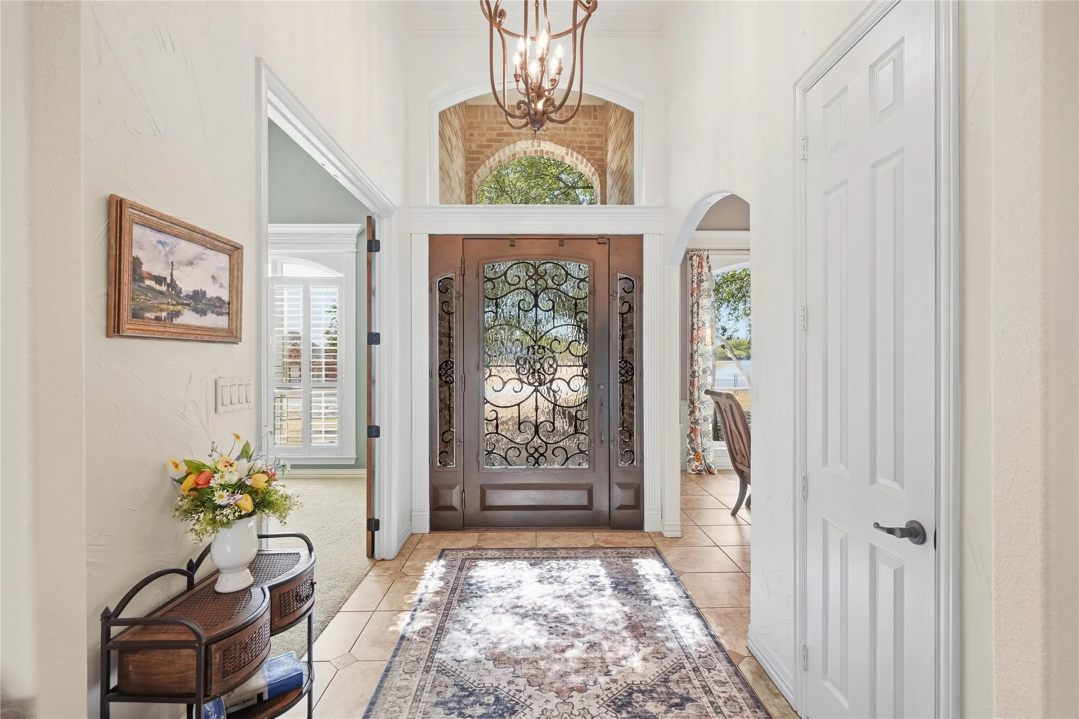 Spectacular oversized front door features decorative wrought -iron scrollwork with glass panels that open up on those cooler days, the arched transom windows fills the foyer with natural light.