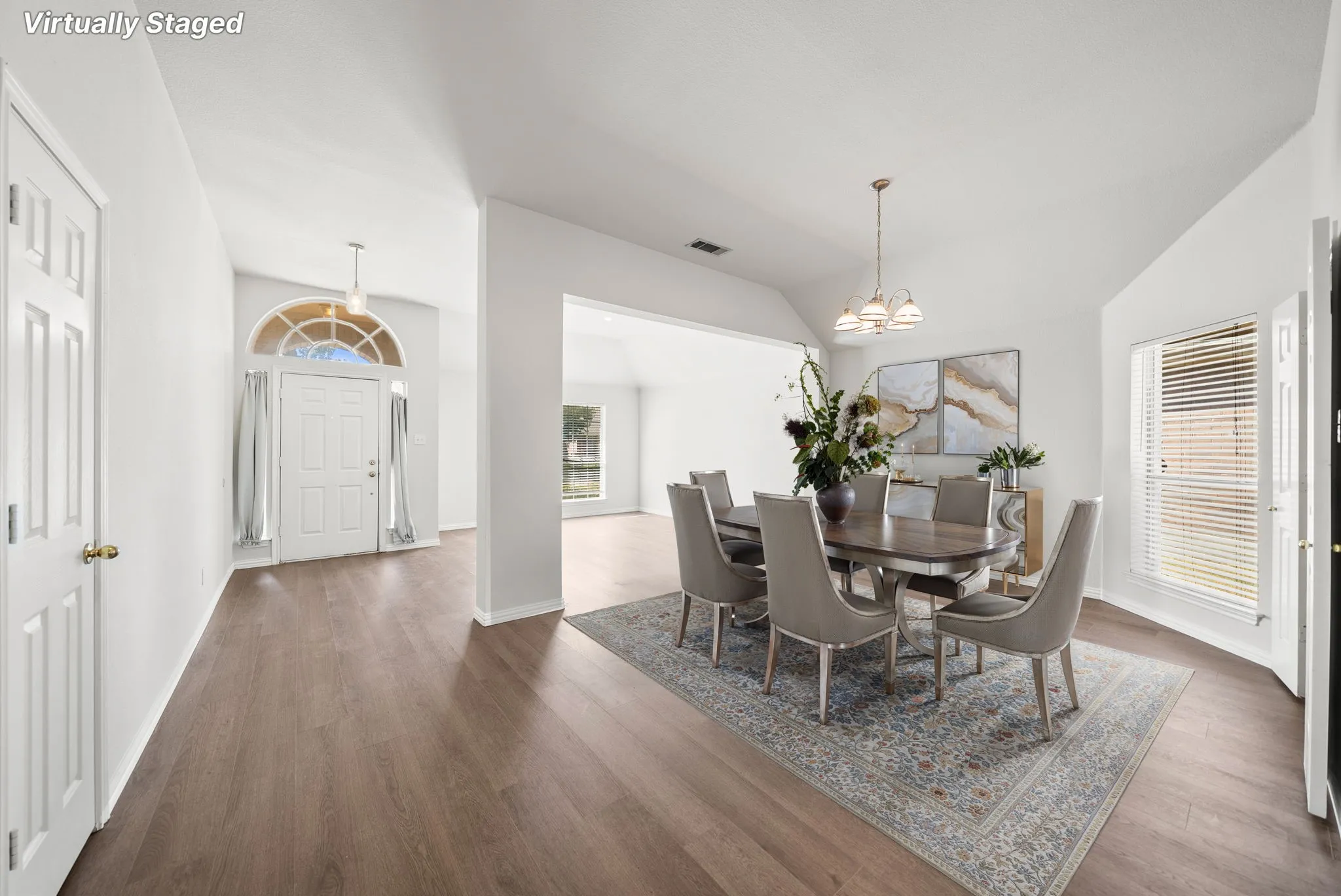 Wood-finish flooring throughout, vaulted ceilings, arched entry window, and an open concept layout
