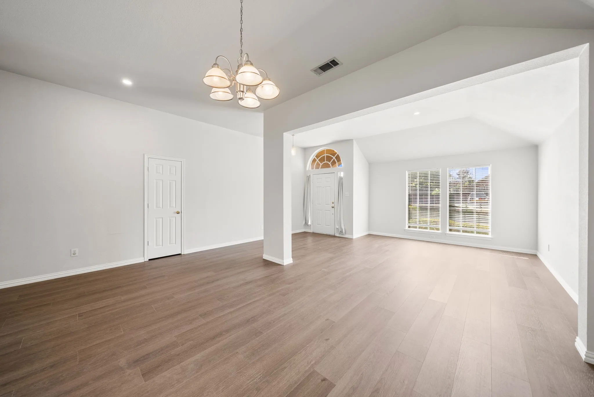 Vaulted ceilings, wood-finish flooring, recessed lighting, and a decorative chandelier
