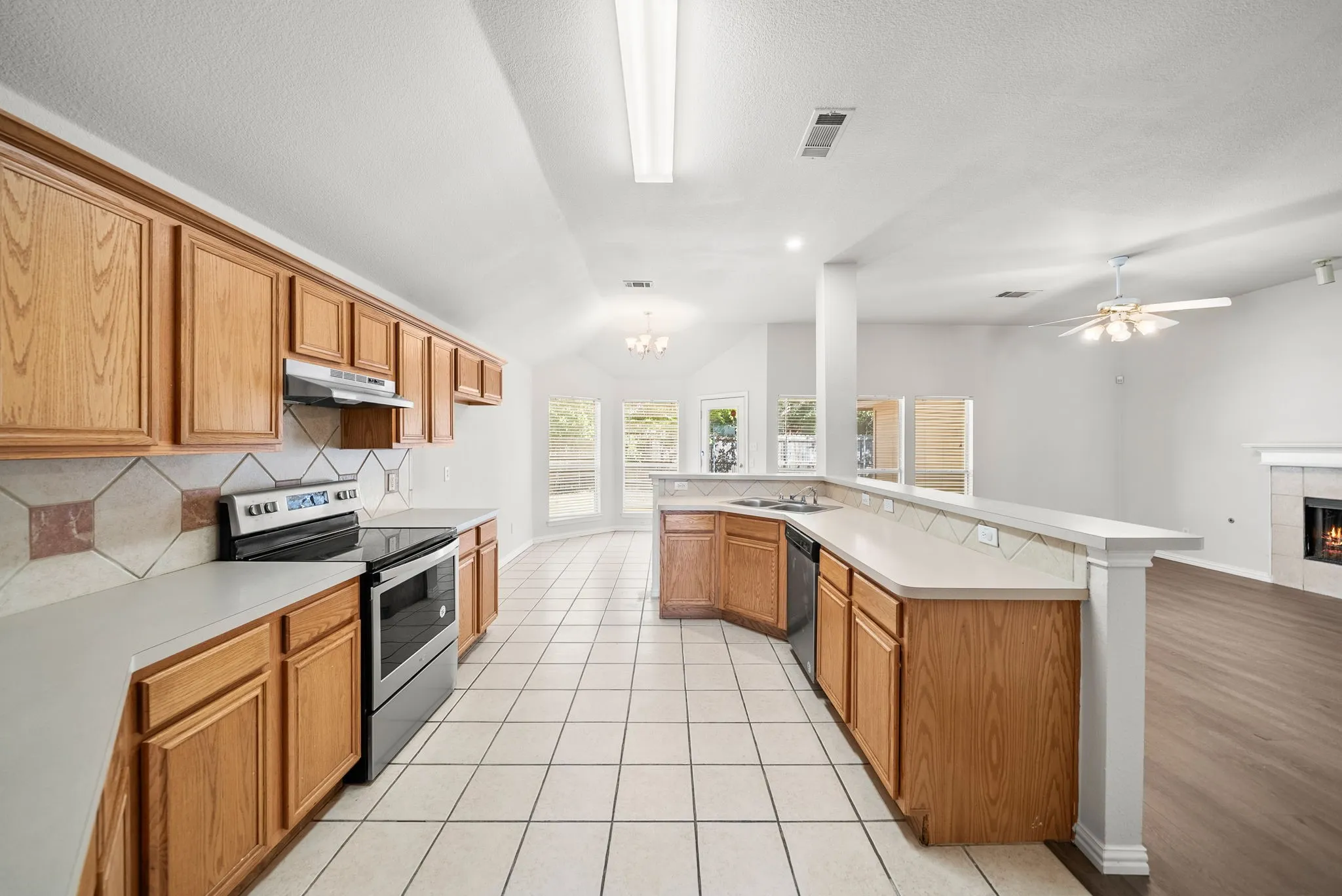 Kitchen featuring wood cabinetry, tile flooring, stainless steel range, and a tile backsplash
