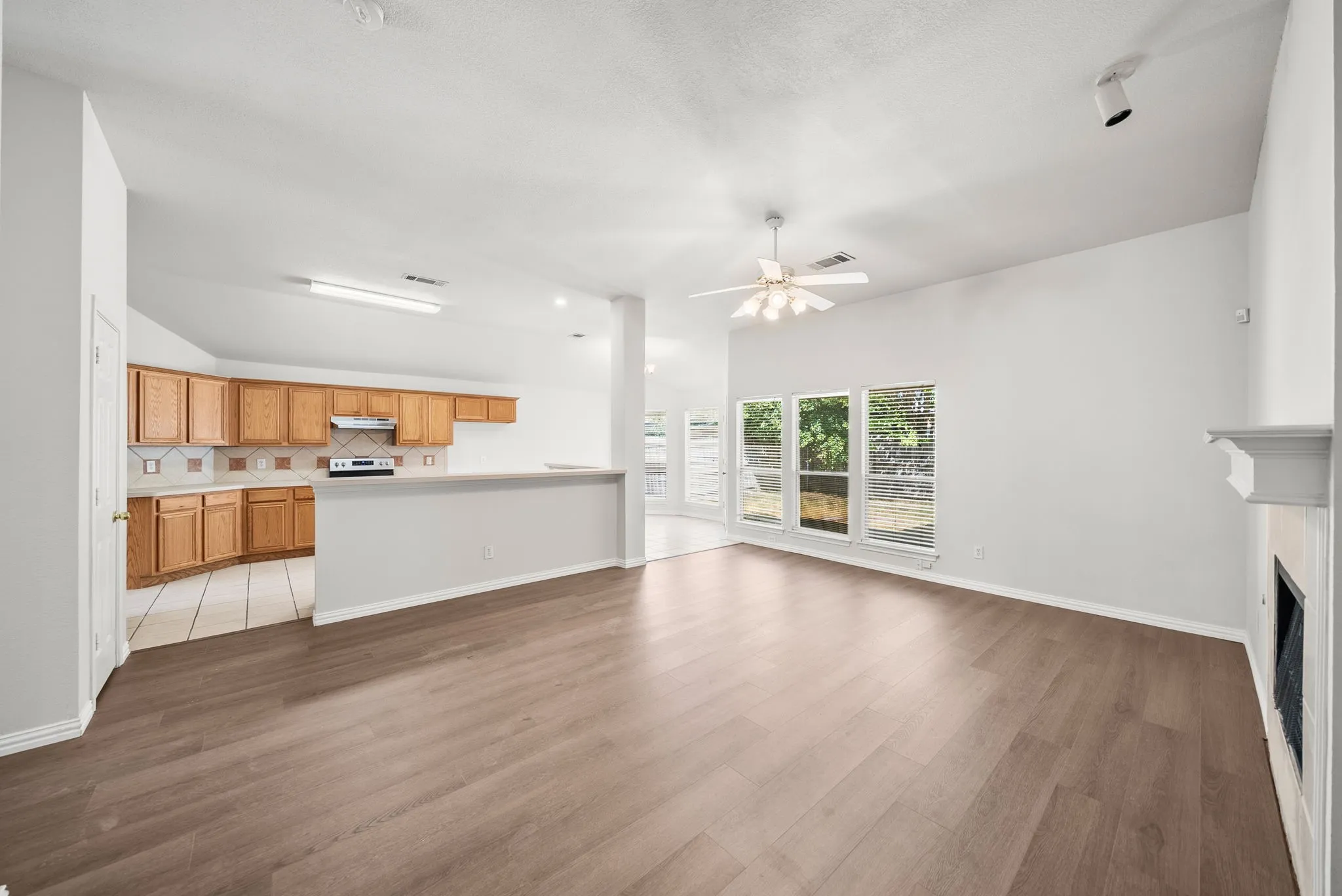 Wood-finish flooring, vaulted ceiling, built-in fireplace, and a ceiling fan with light
