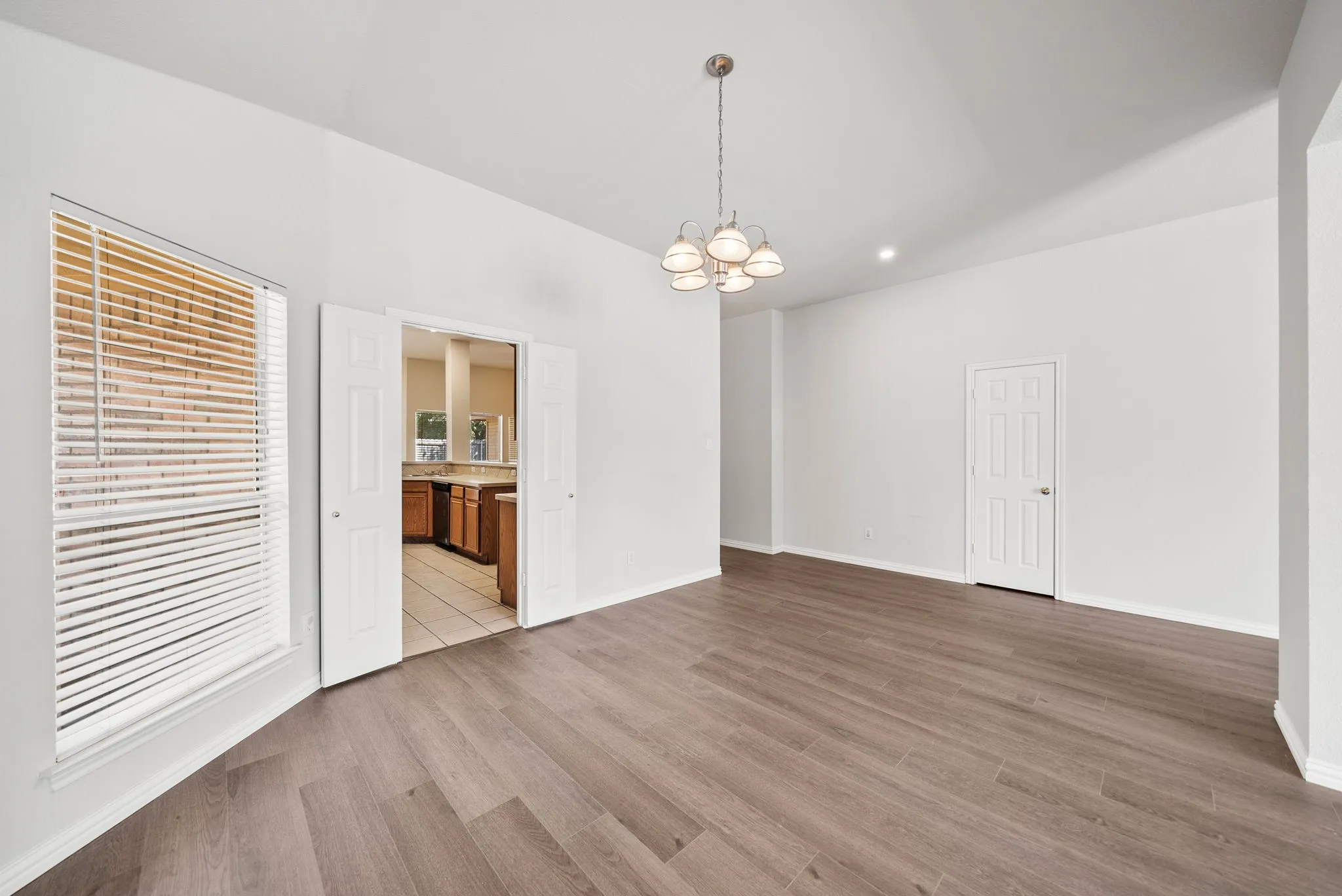 Wood-finish flooring with vaulted ceilings, recessed lighting, and a chandelier