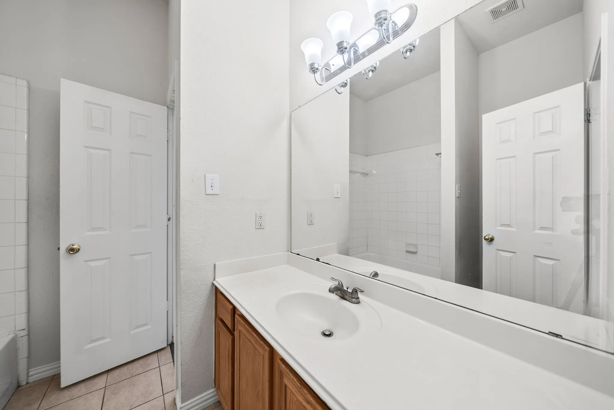 Integrated vanity with wood-finish cabinetry, a single basin sink, and a chrome faucet