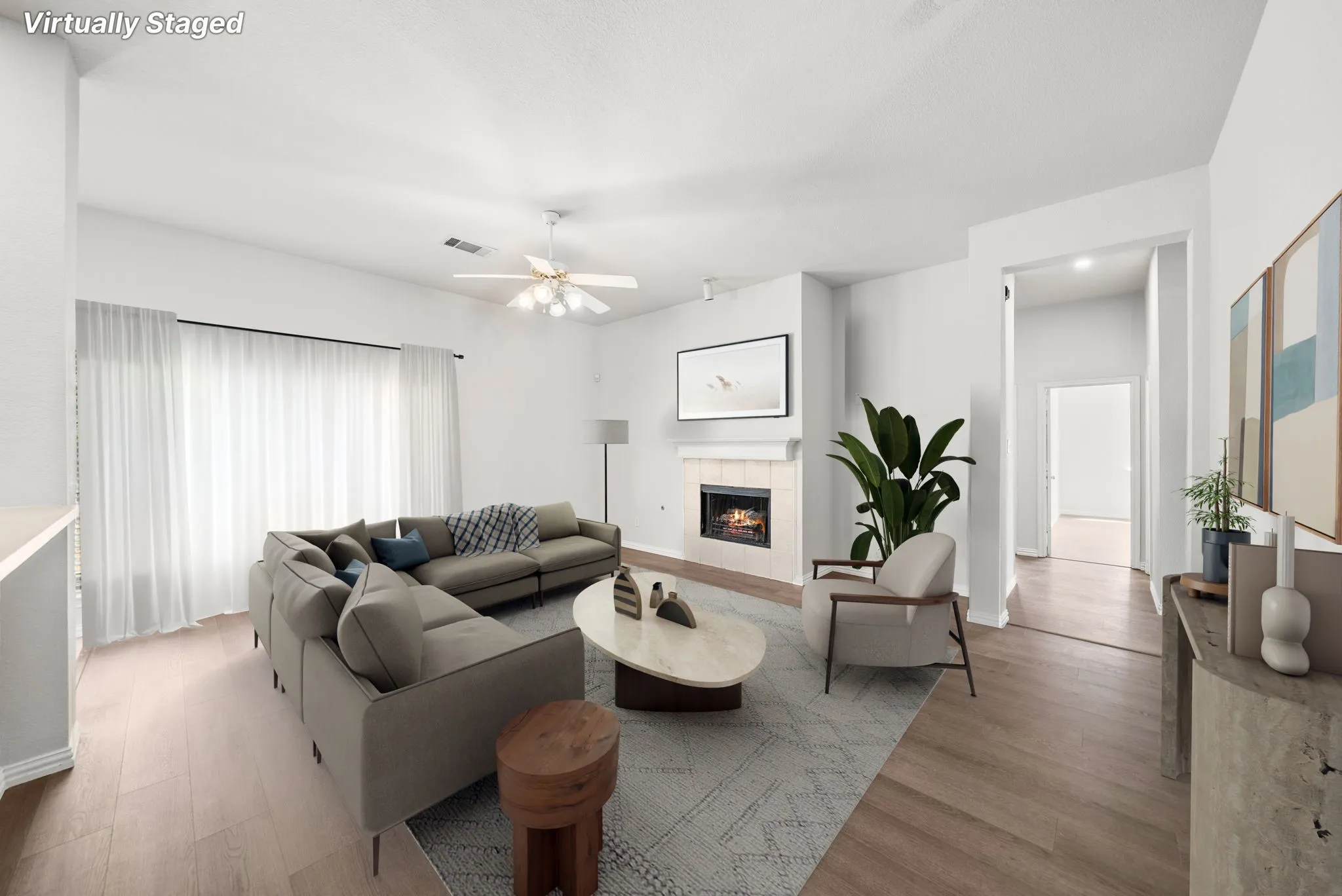 Wood-finish flooring throughout, a ceiling fan with integrated lighting, and a fireplace featuring a light-toned surround