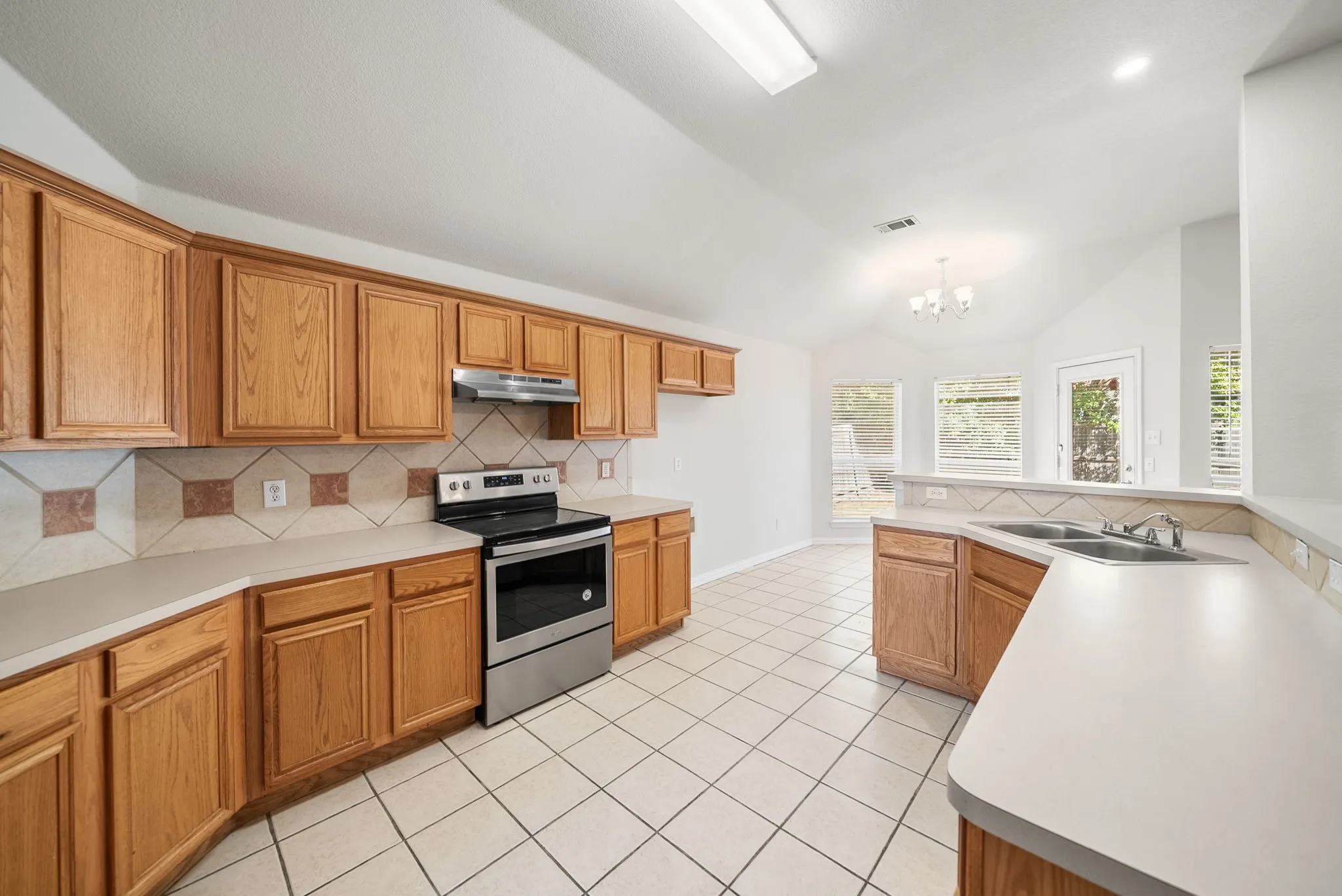 Kitchen with abundant wood cabinetry, stainless steel range and range hood, and tile flooring