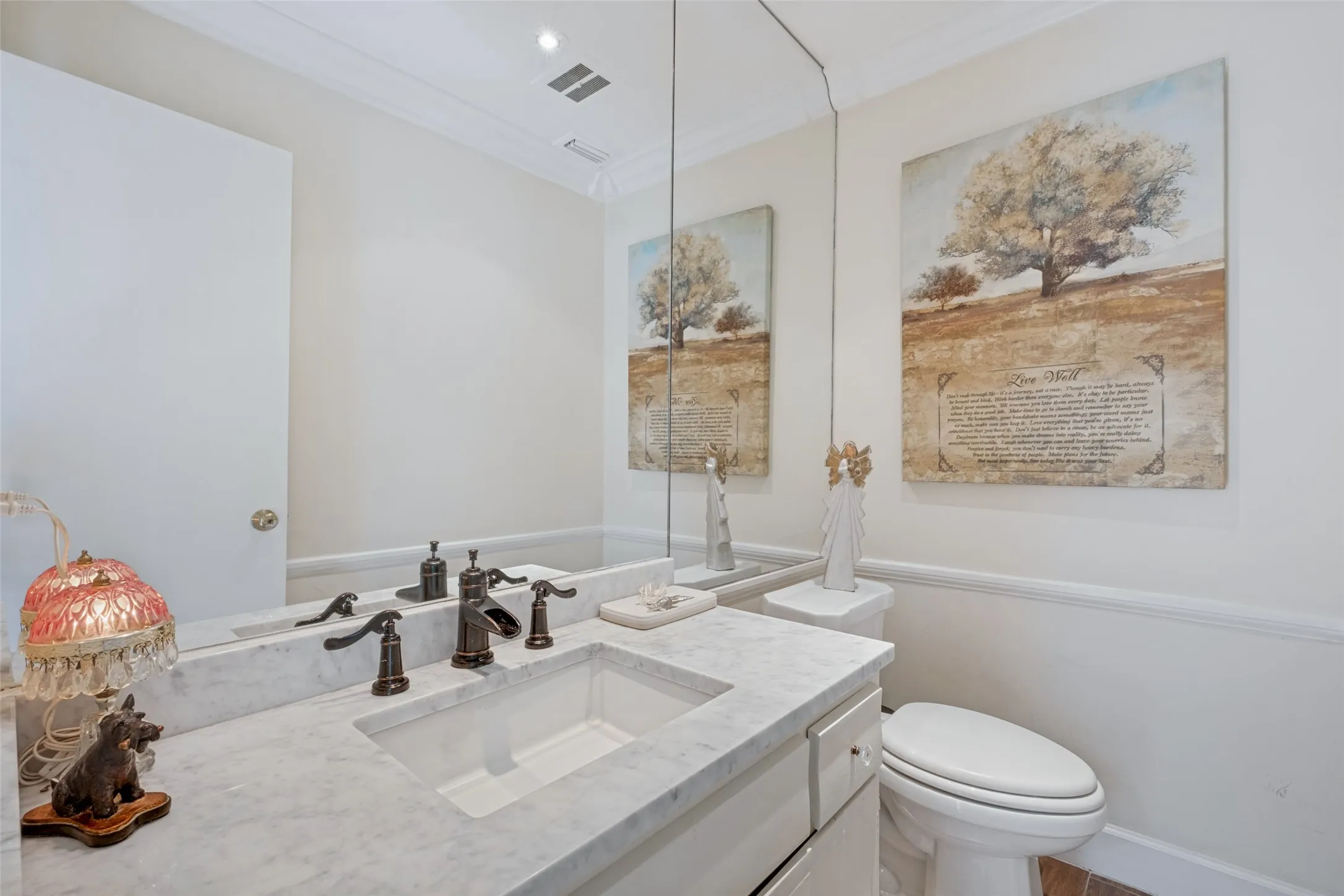 Vanity with a white undermount sink, marble-finish countertop, and bronze-finish fixtures