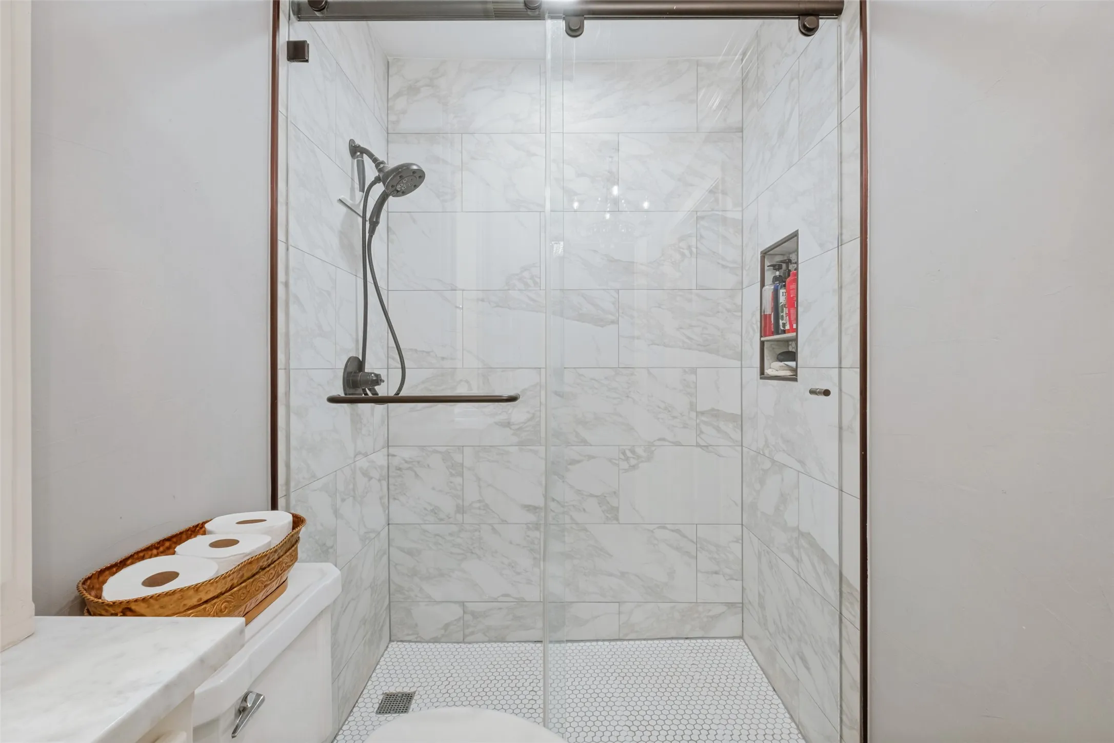 Frameless glass shower enclosure with a dark bronze hardware finish