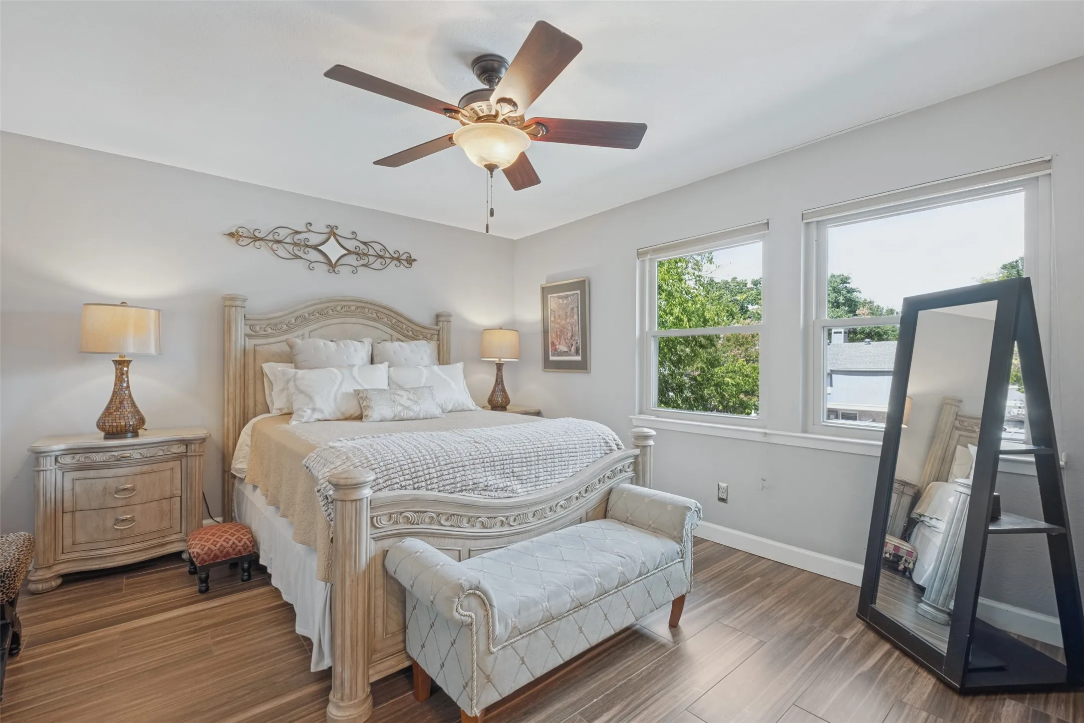 Wood-finish flooring, dual windows with natural light, ceiling fan with integrated lighting, and neutral wall tones