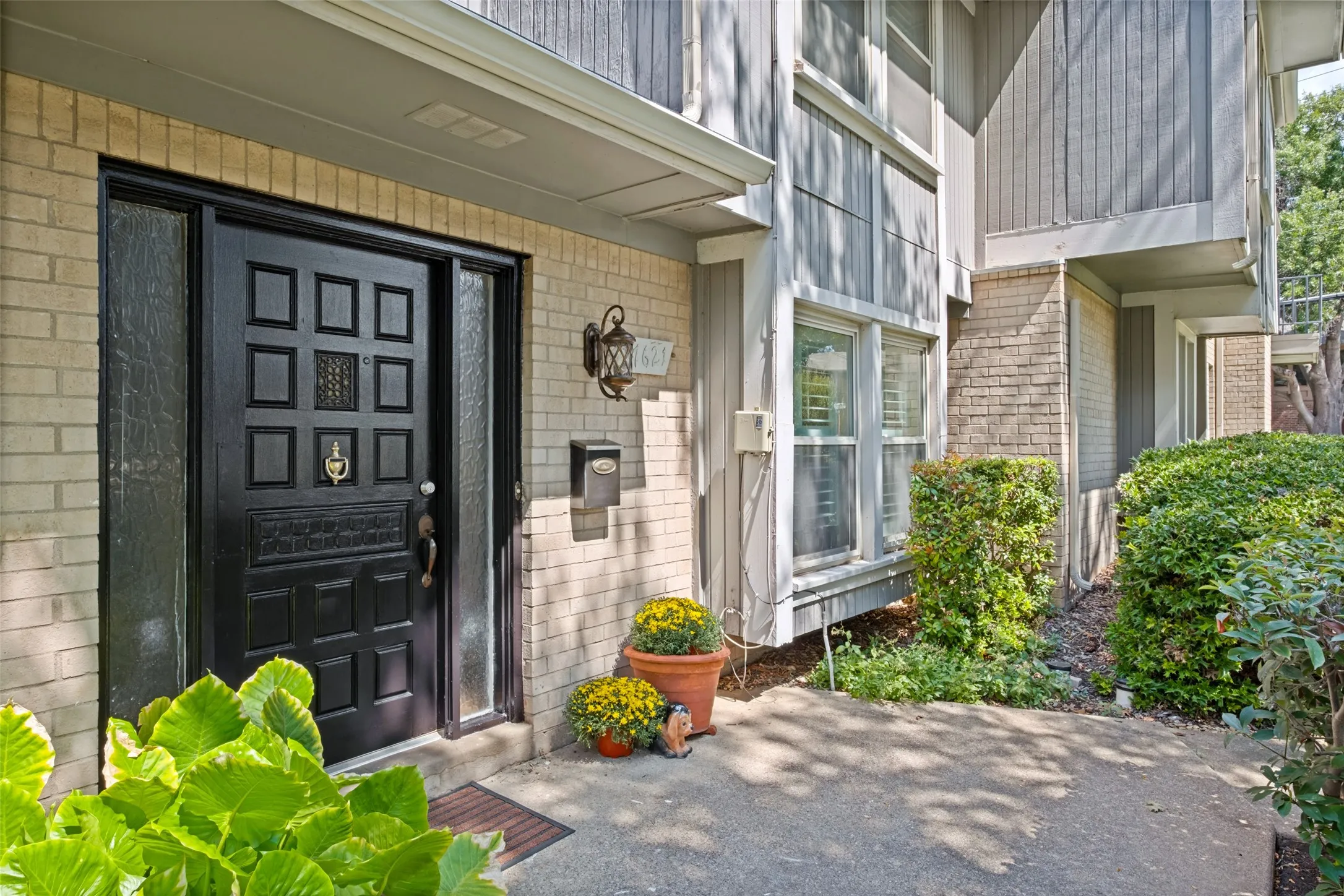 Brick and wood-paneled exterior with a black paneled entry door