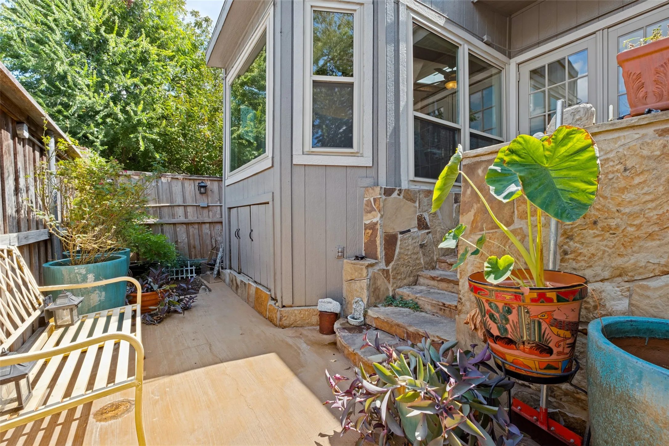 Exterior featuring stone-clad steps, a wood privacy fence, and multiple window panels