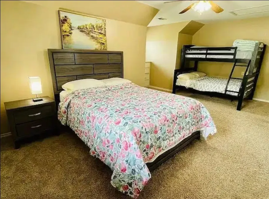 Carpeted bedroom featuring a textured accent wall, ceiling fan, and built-in dresser