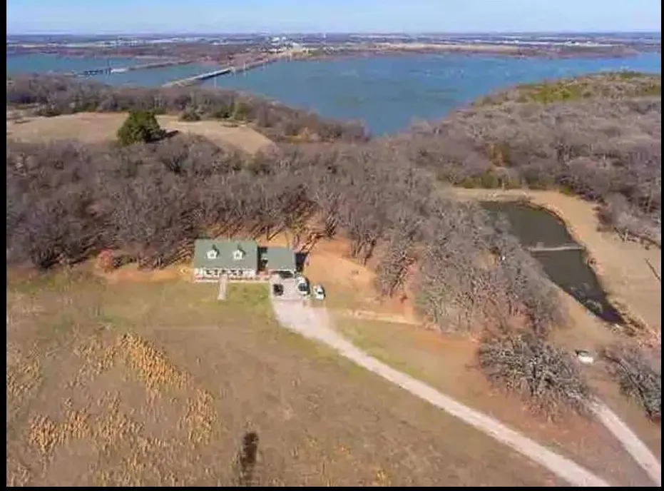 Waterfront property featuring a residential structure with a green roof, two dormer windows, and an expansive natural landscape