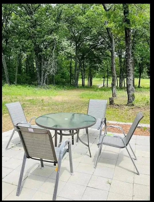 Paved patio area, surrounded by mature trees, and natural green landscaping