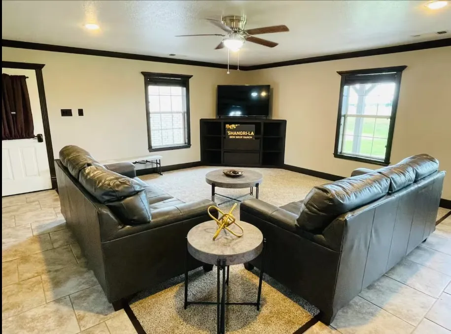 Recessed lighting, ceiling fan, built-in entertainment console, two large windows, and tile flooring