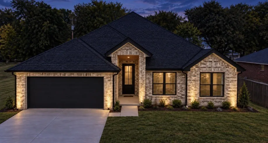 Modern brick facade with dark-framed windows, a dark shingle roof, an attached garage with a dark door, and front yard landscaping