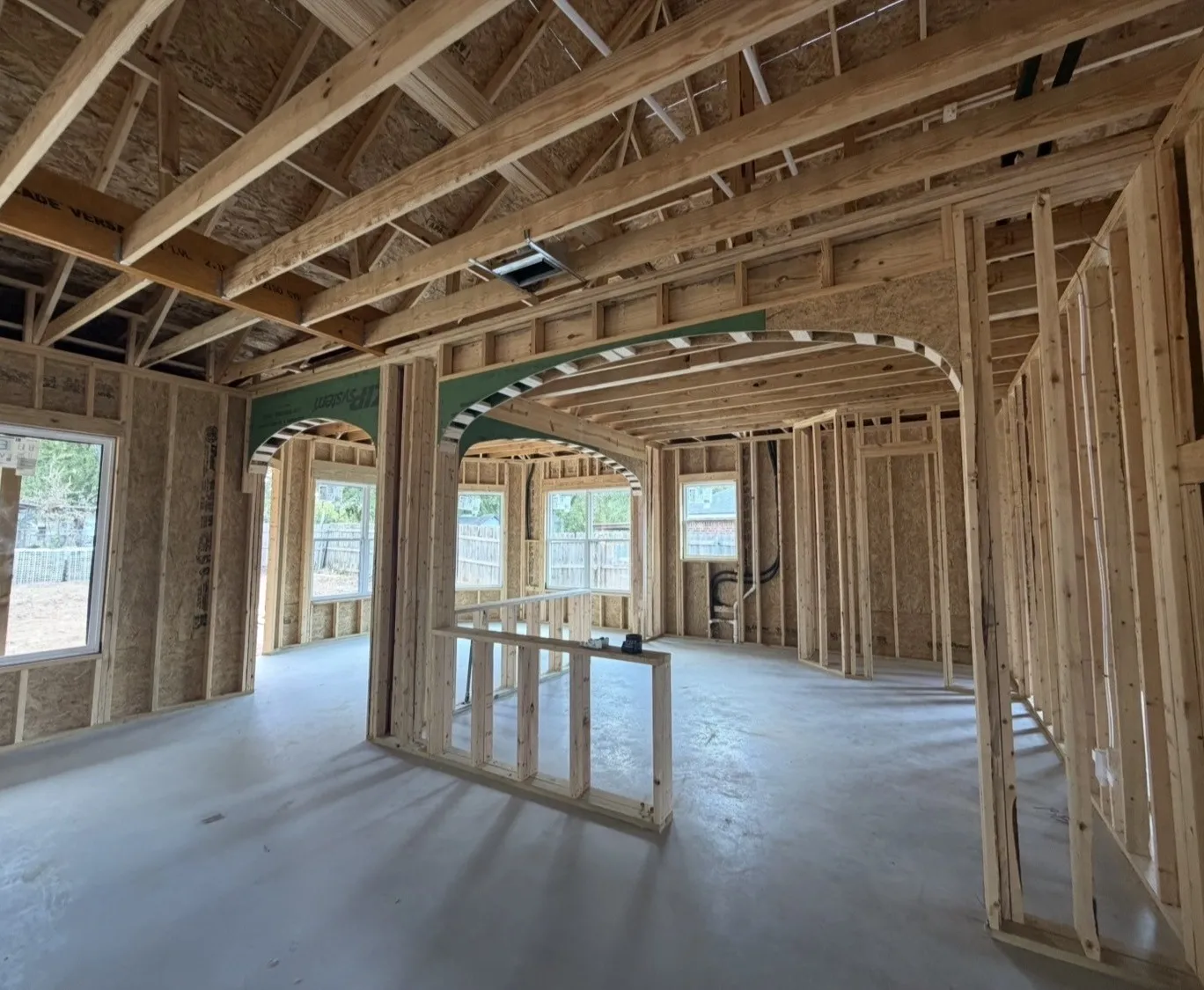 Open-concept framing with vaulted ceiling, multiple windows, and decorative arched doorways