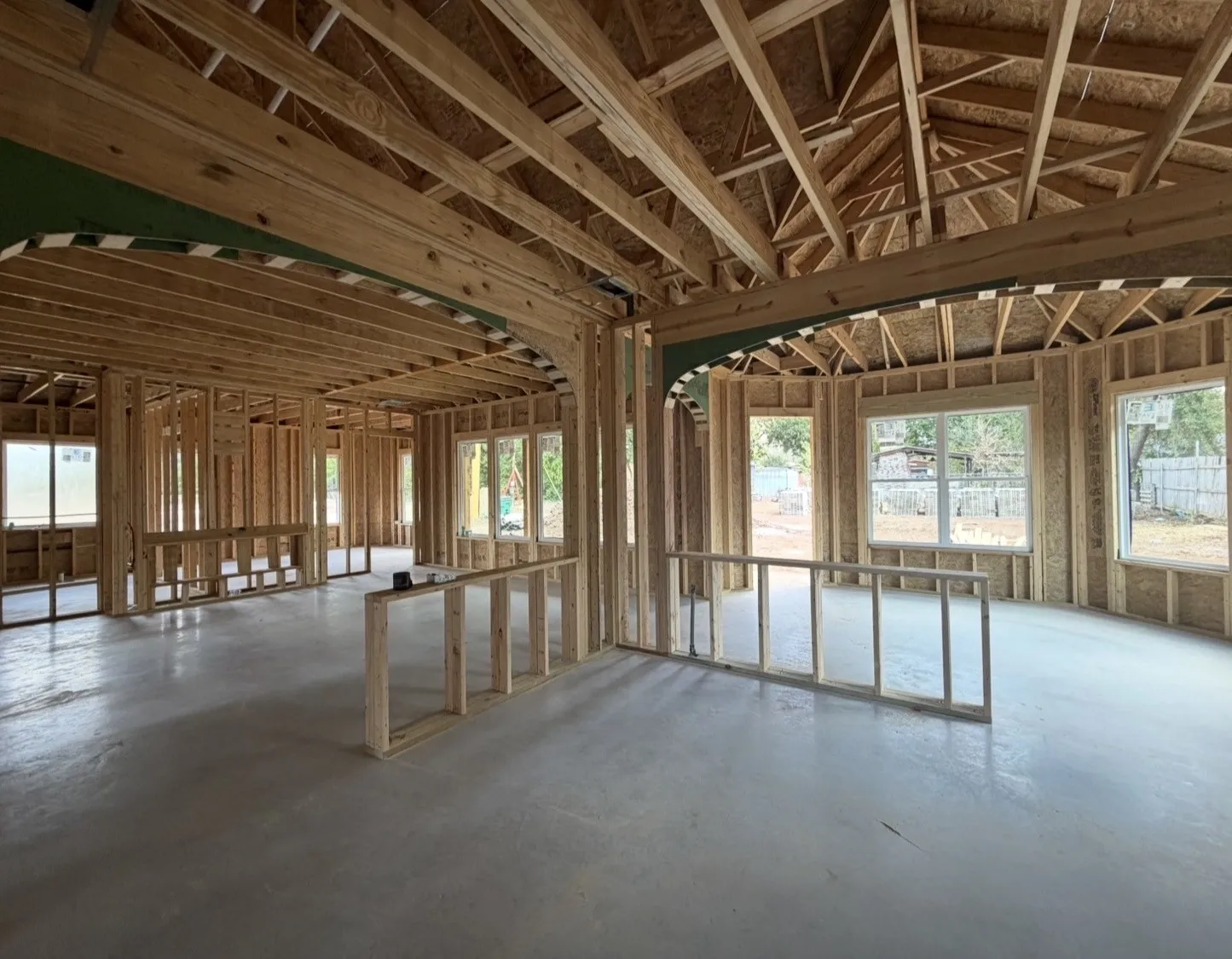 Expansive open framing with an arched entryway, multiple windows, and a high-pitched roof structure