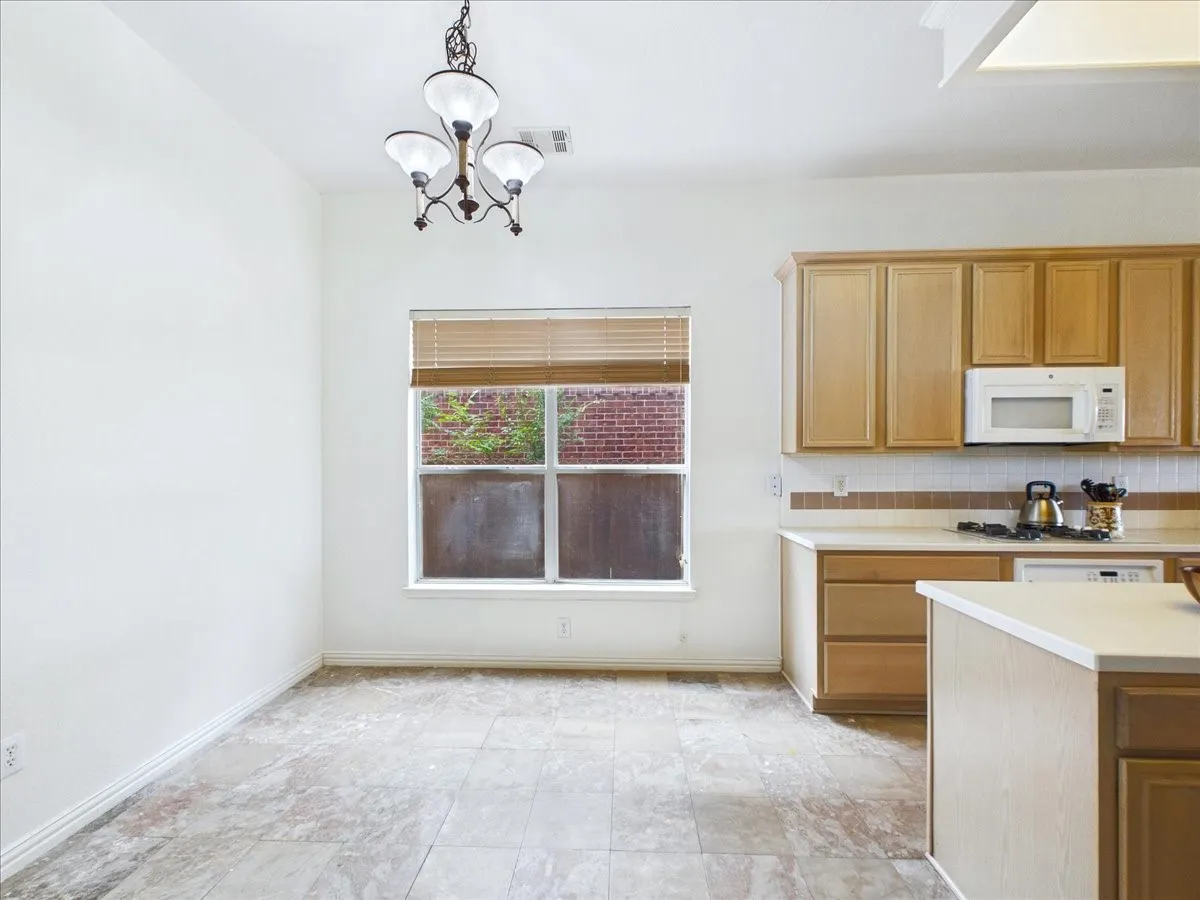 Tiled flooring, built-in cabinetry, window with blinds, overhead lighting fixture, and a built-in microwave