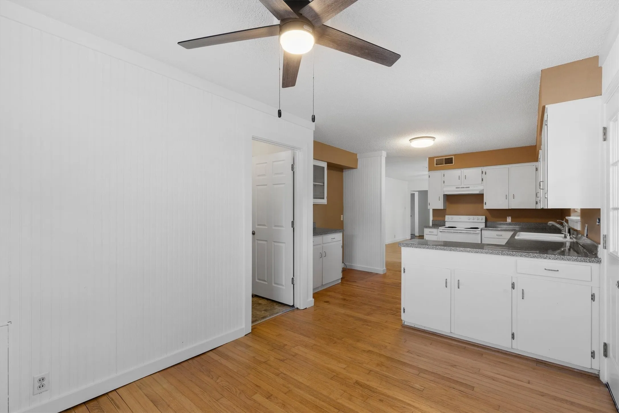 Kitchen featuring white cabinetry, grey countertops, a white electric range, and a ceiling fan with integrated lighting