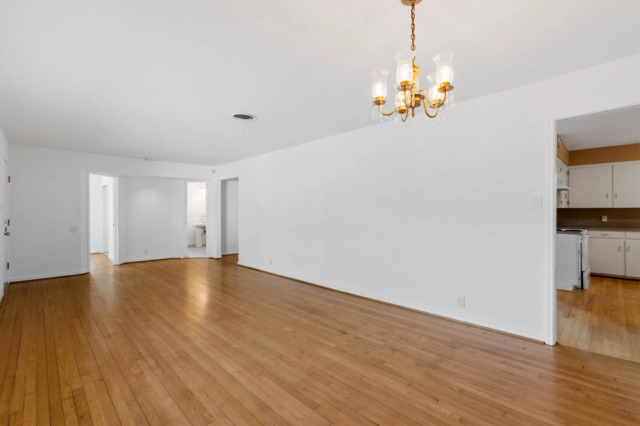 Hardwood flooring, recessed lighting, and a brass chandelier