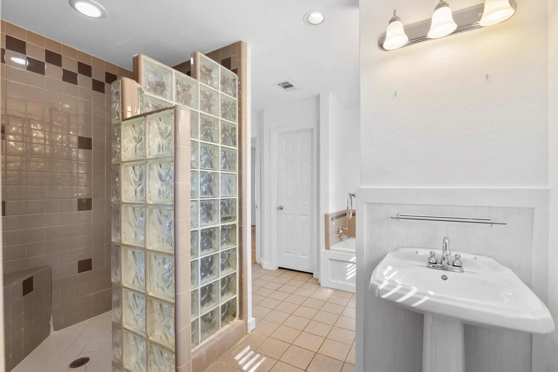 Tiled shower enclosure with glass block partition and integrated bench