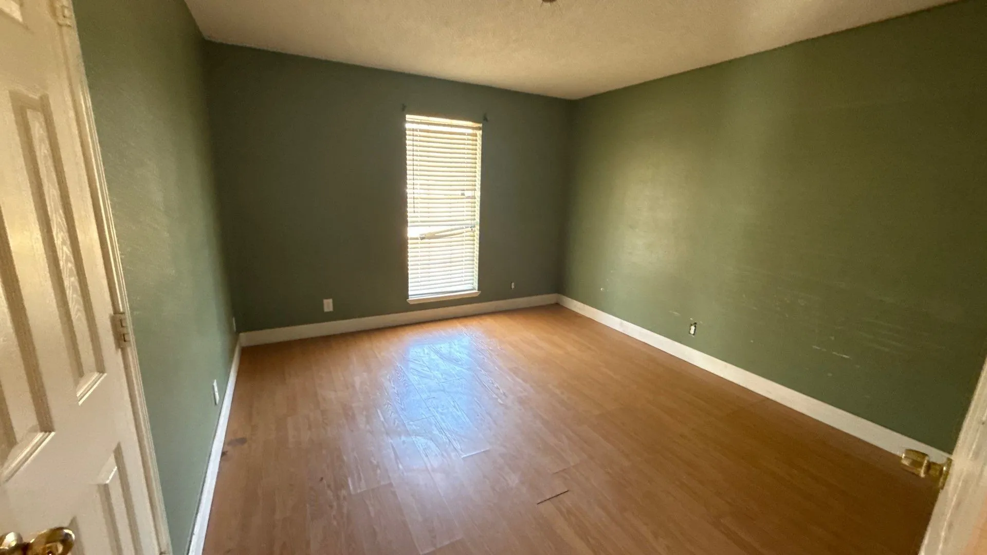 Bedroom 2 Wood-finish flooring with white trim and a single window with horizontal blinds