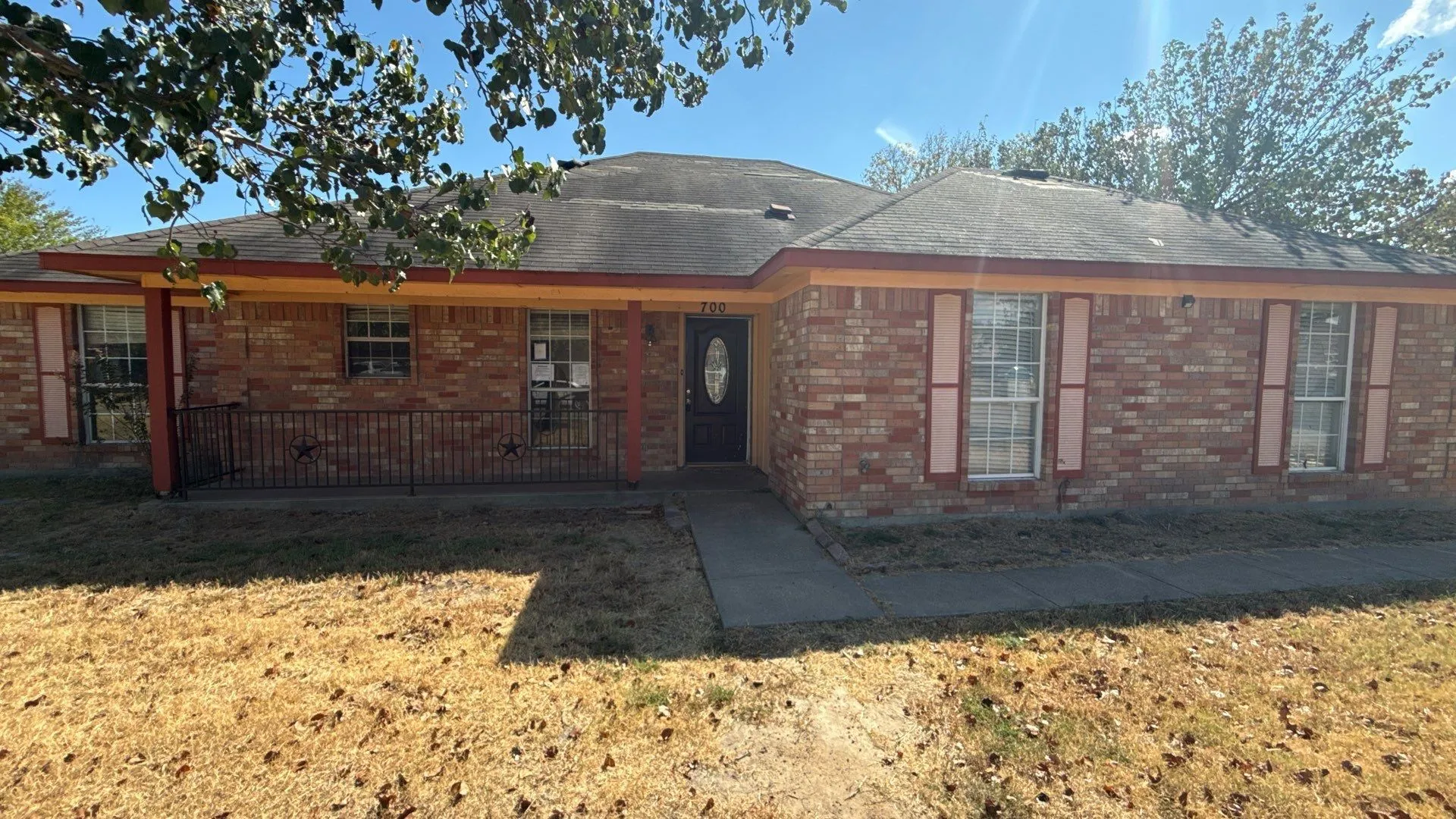 Brick exterior with a covered porch featuring decorative iron railing