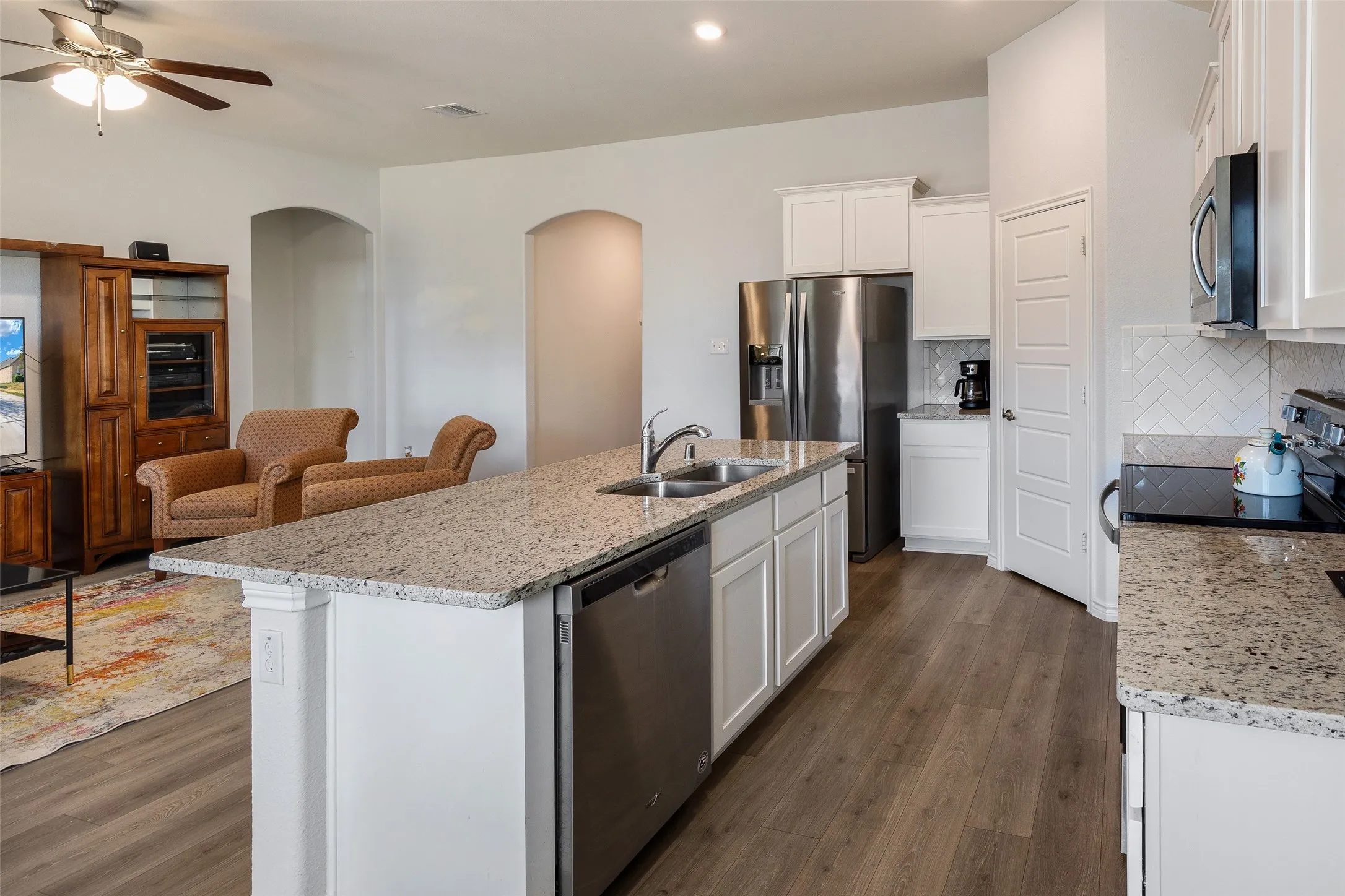 Kitchen featuring white cabinetry, granite countertops, wood-finish flooring, and stainless steel appliances