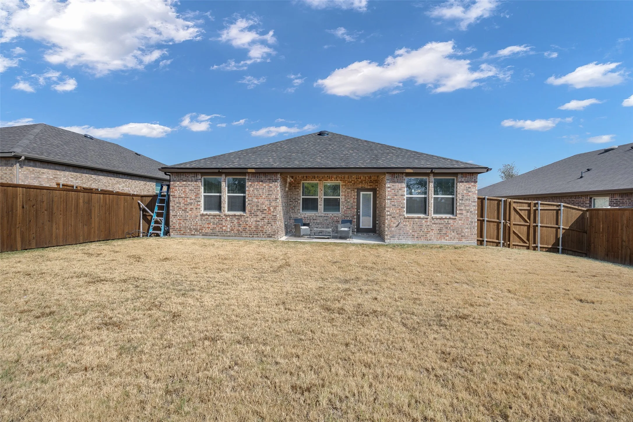 Brick exterior with a dark-shingle roof, offering a rear patio area
