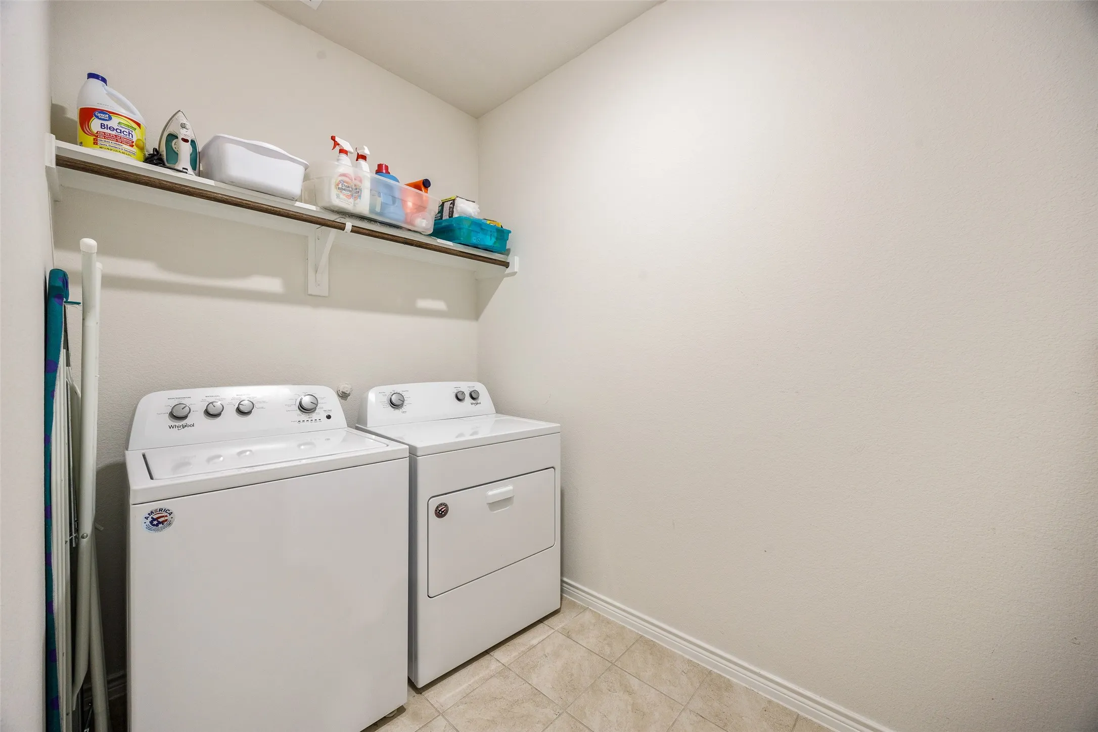 Dedicated laundry space with a built-in shelf for storage and tile flooring