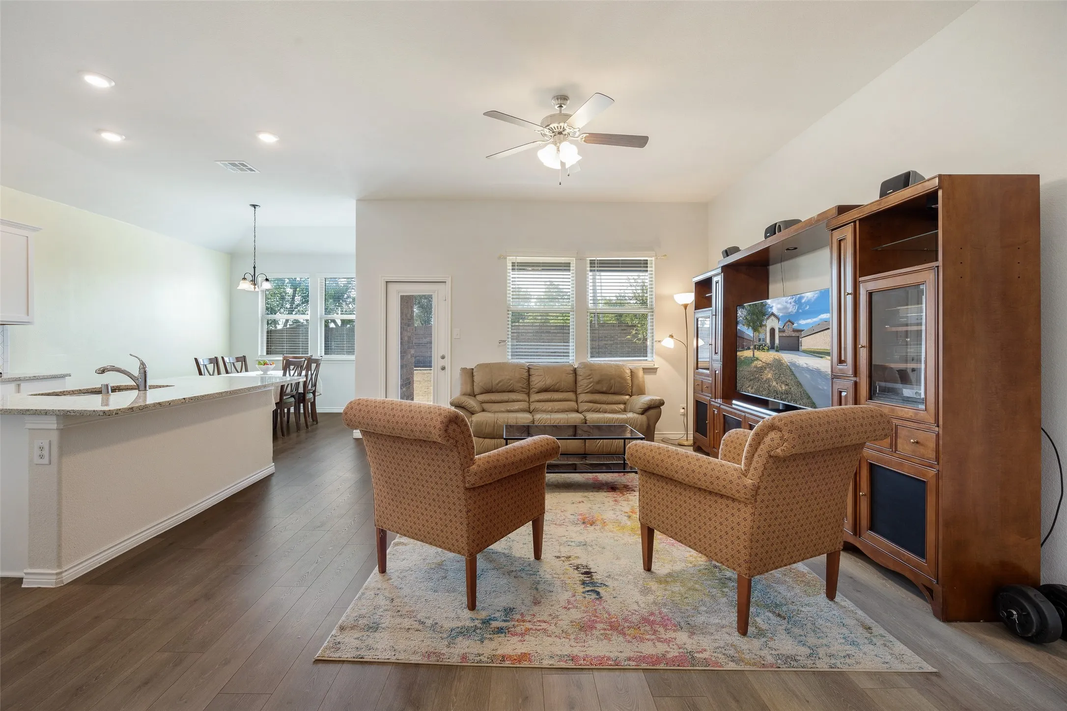 Open-concept living space featuring wood-finish flooring, recessed lighting, and a ceiling fan