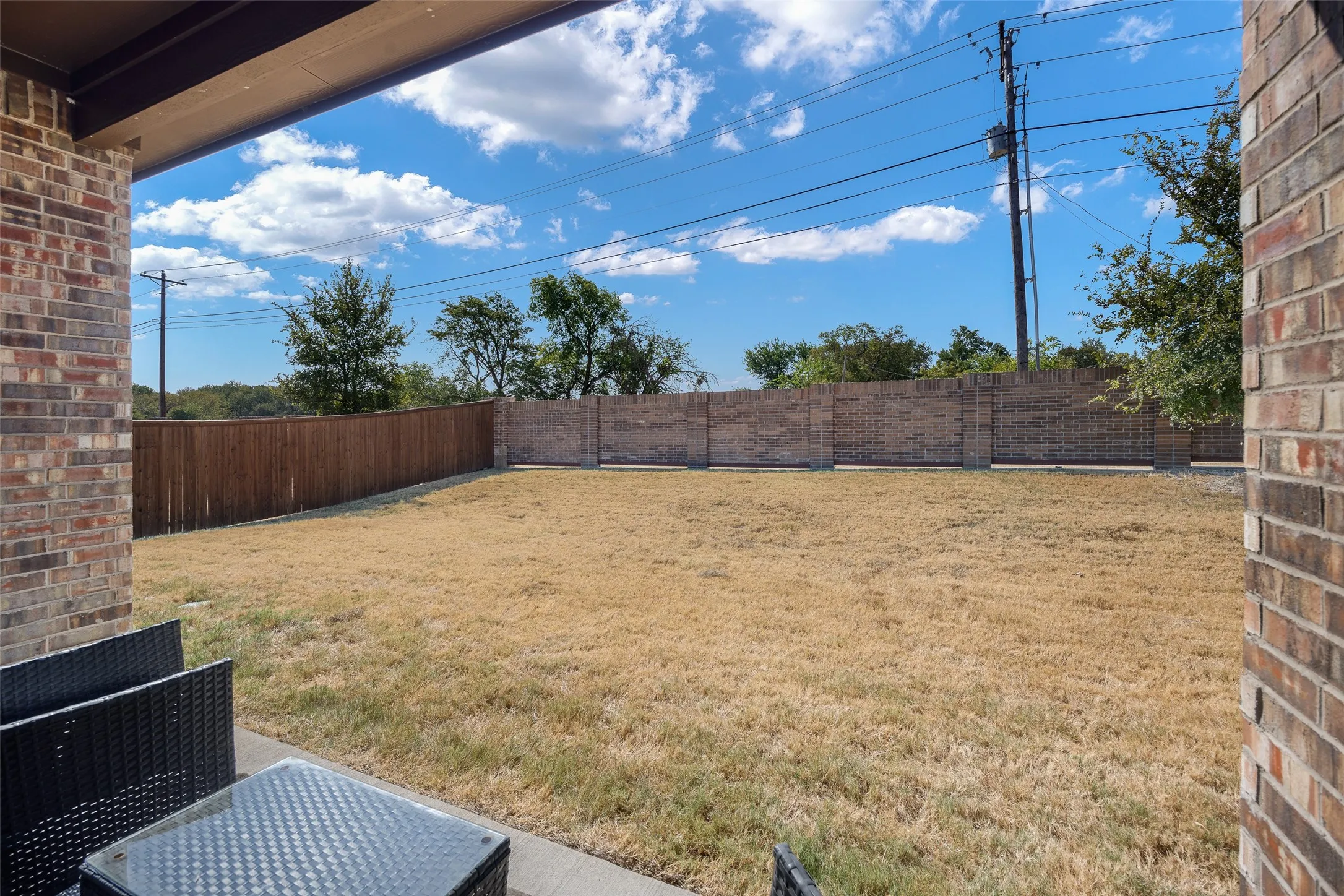 Expansive outdoor space featuring a concrete patio, brick exterior wall, and a combination of wood and brick privacy fencing
