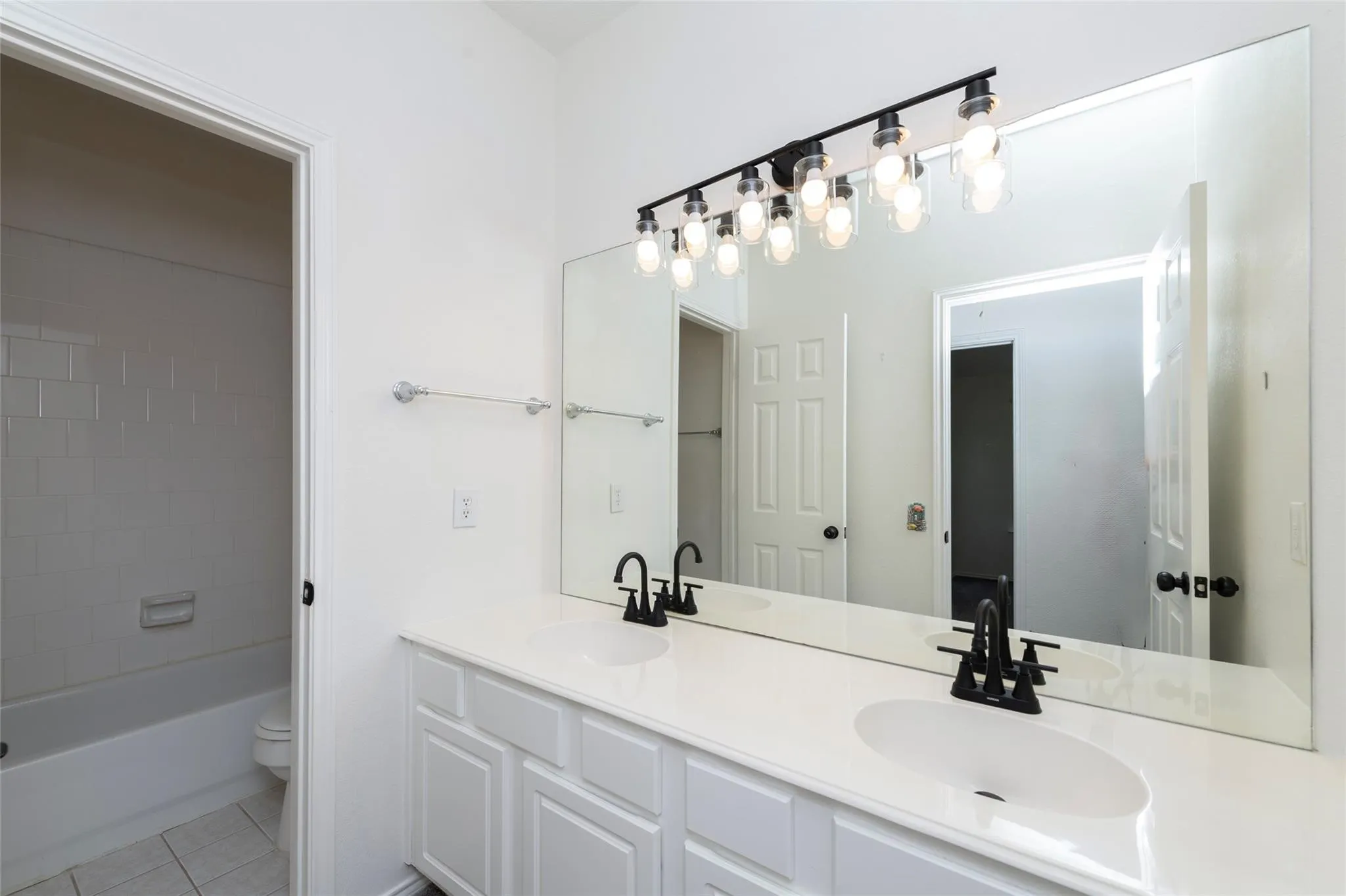 Dual vanity with white cabinetry, integrated sinks, white countertop, and matte black fixtures