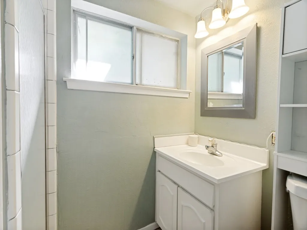 Single vanity with white cabinetry, integrated sink, and chrome faucet