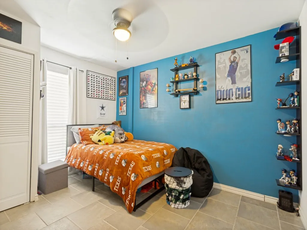 Light-colored tile flooring, ceiling fan with integrated lighting, louvered closet doors, and window with blinds