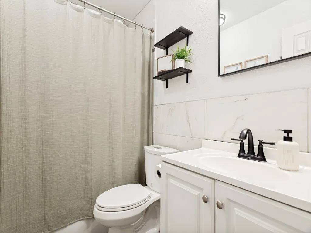 White vanity with dual doors, single basin sink, matte black faucet, and white countertop