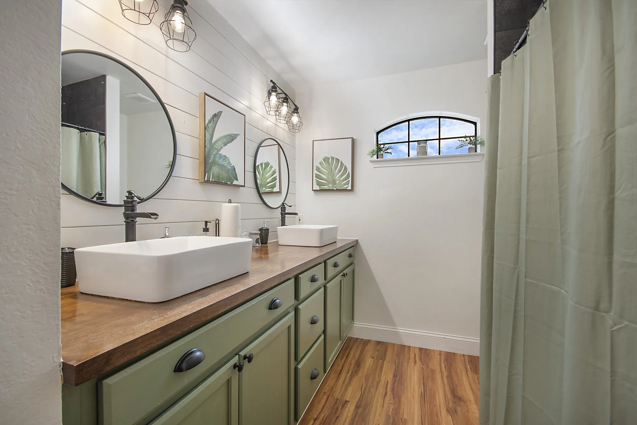 Secondary bath with double vessel sinks, butcher-block counter and shiplap wall.