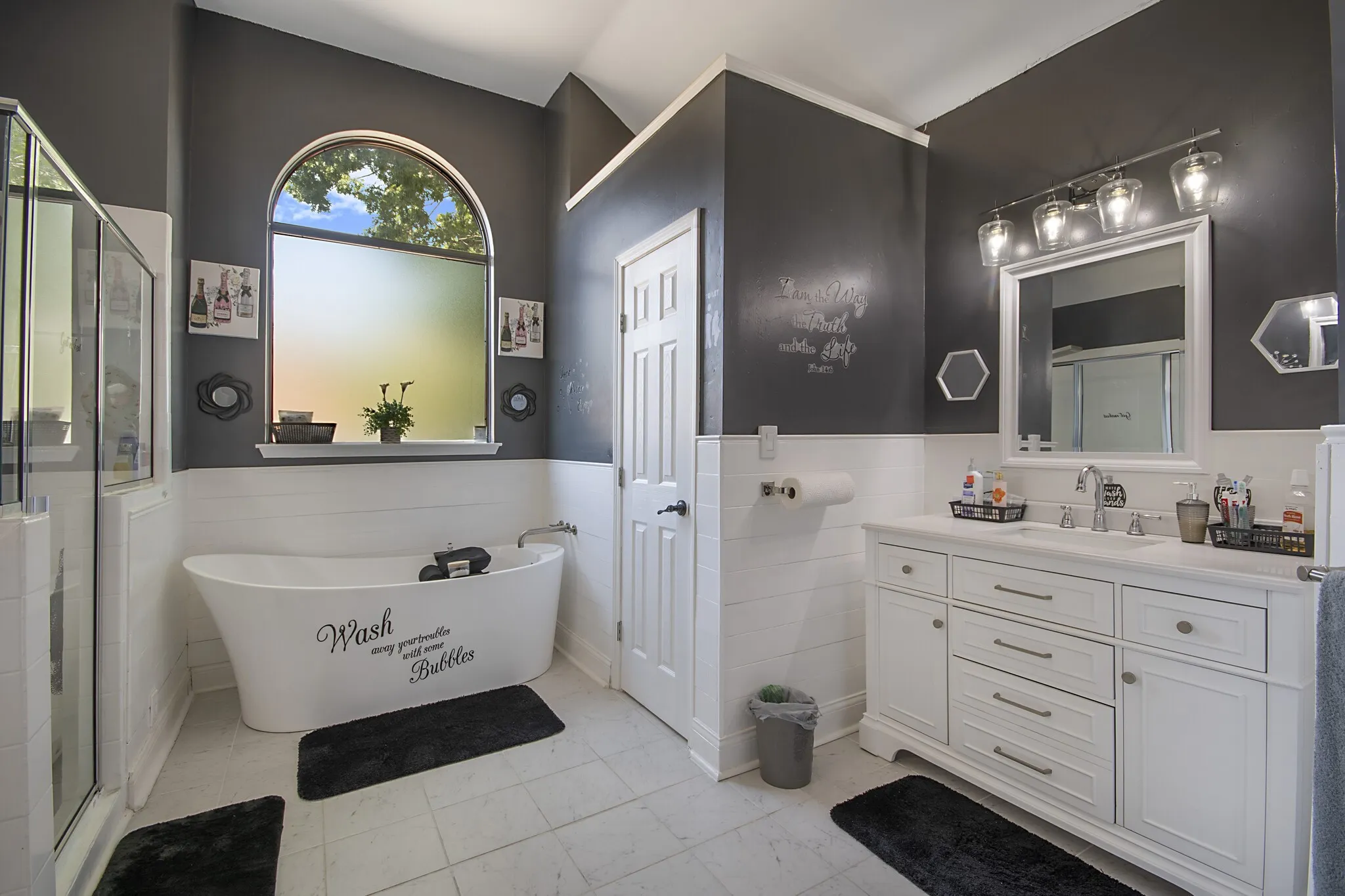 Primary bath with a freestanding soaking tub beneath an arched window.