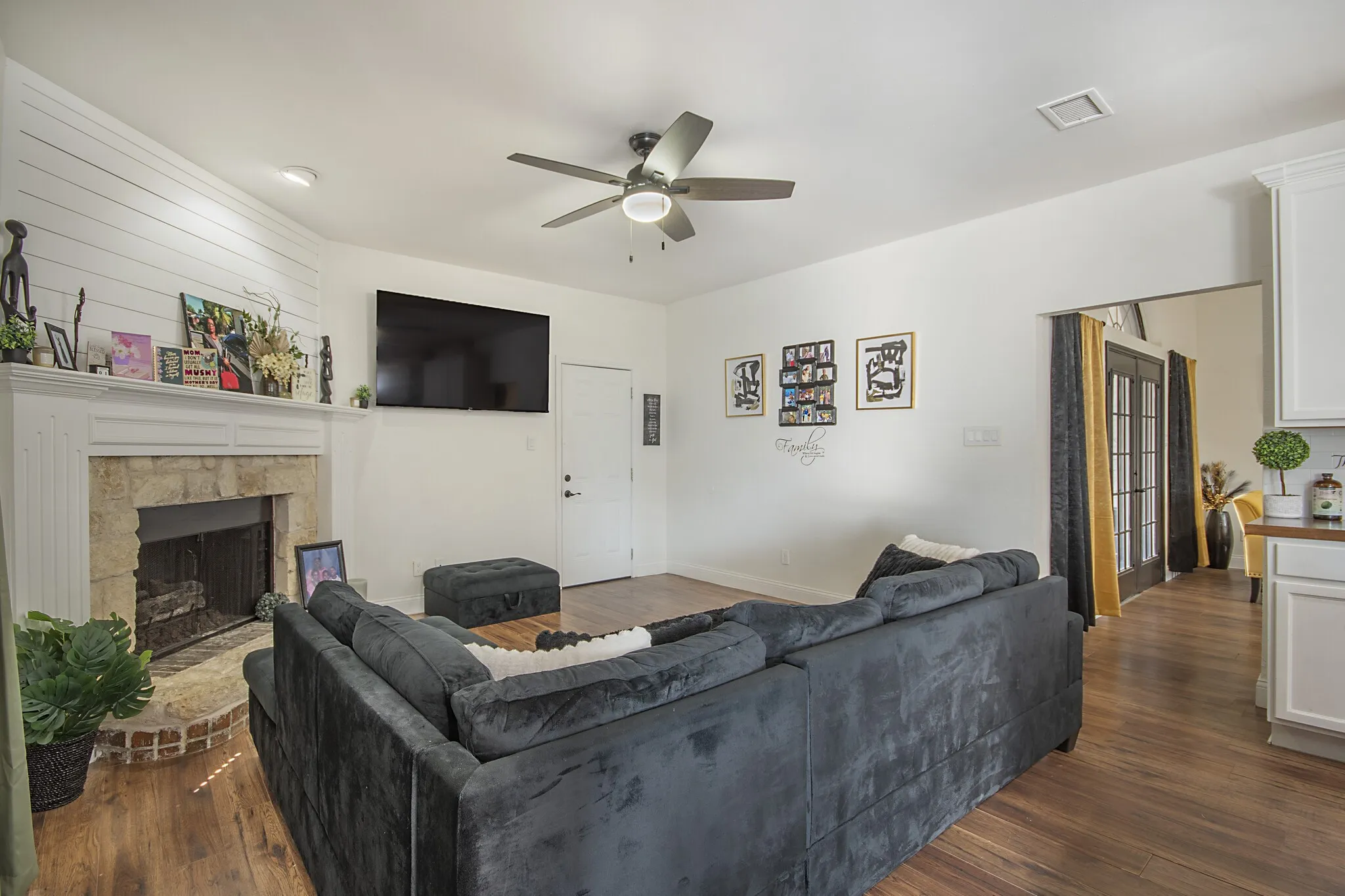 Family room open to the kitchen, with a stone fireplace.