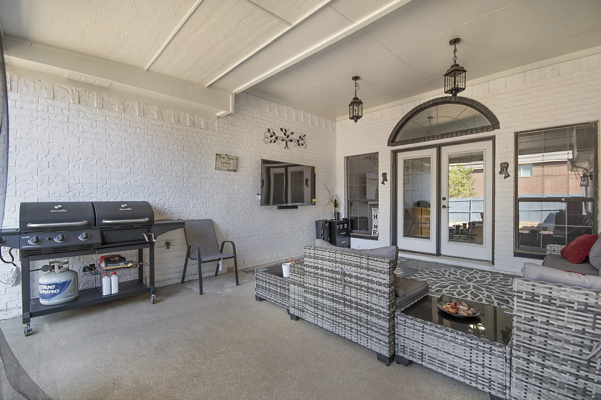 Covered patio in painted brick, sized for a full outdoor living set and grills.