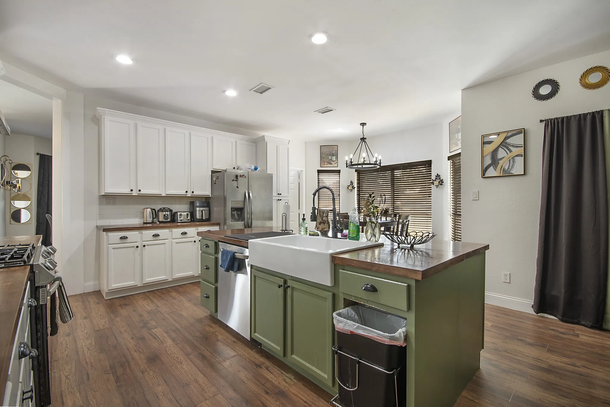 Kitchen with farmhouse sink, butcher-block island top and stainless appliances.